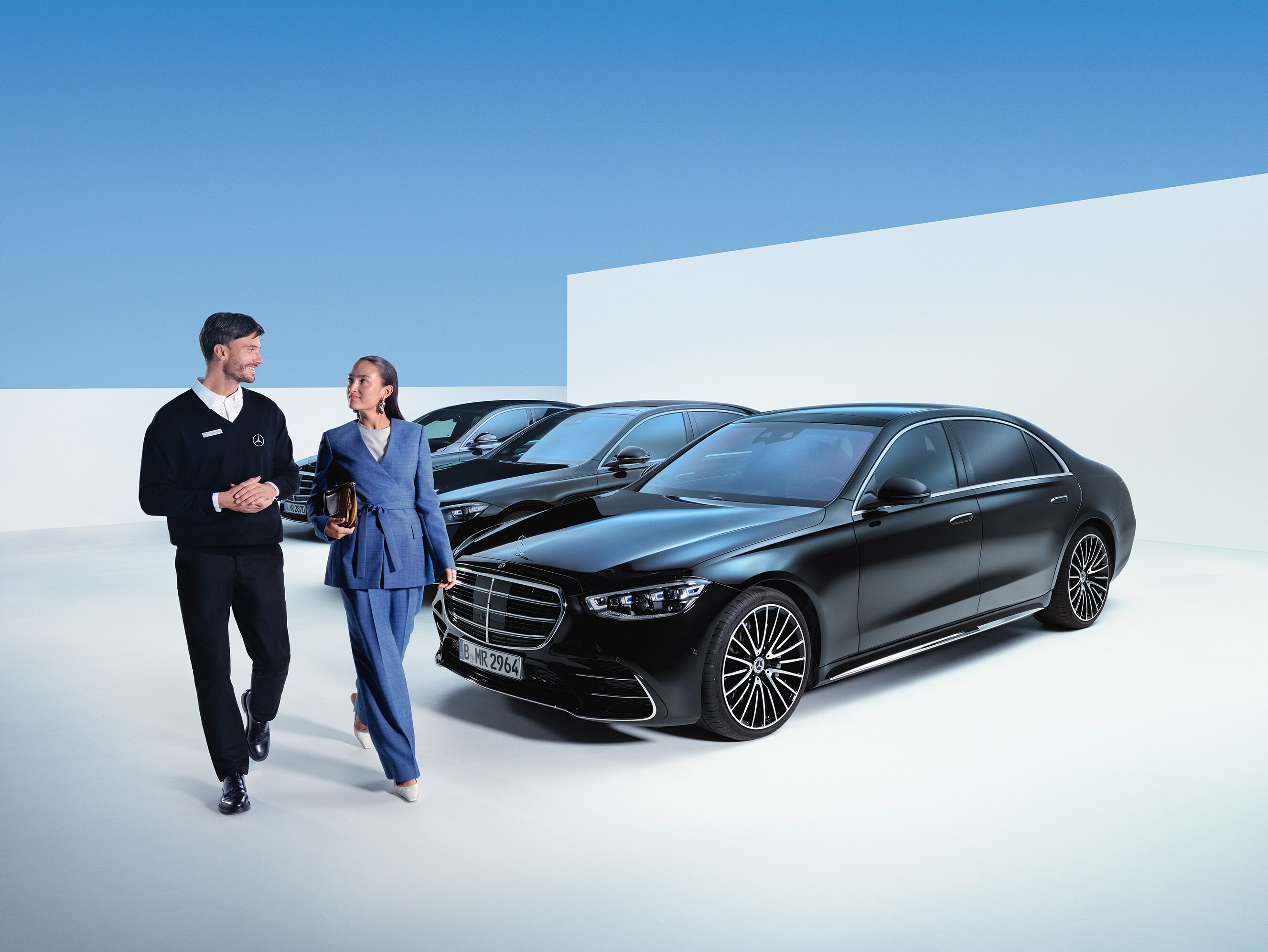 Kvinna och Mercedes-Benz medarbetare går vid rad av Mercedes-Benz bilar
