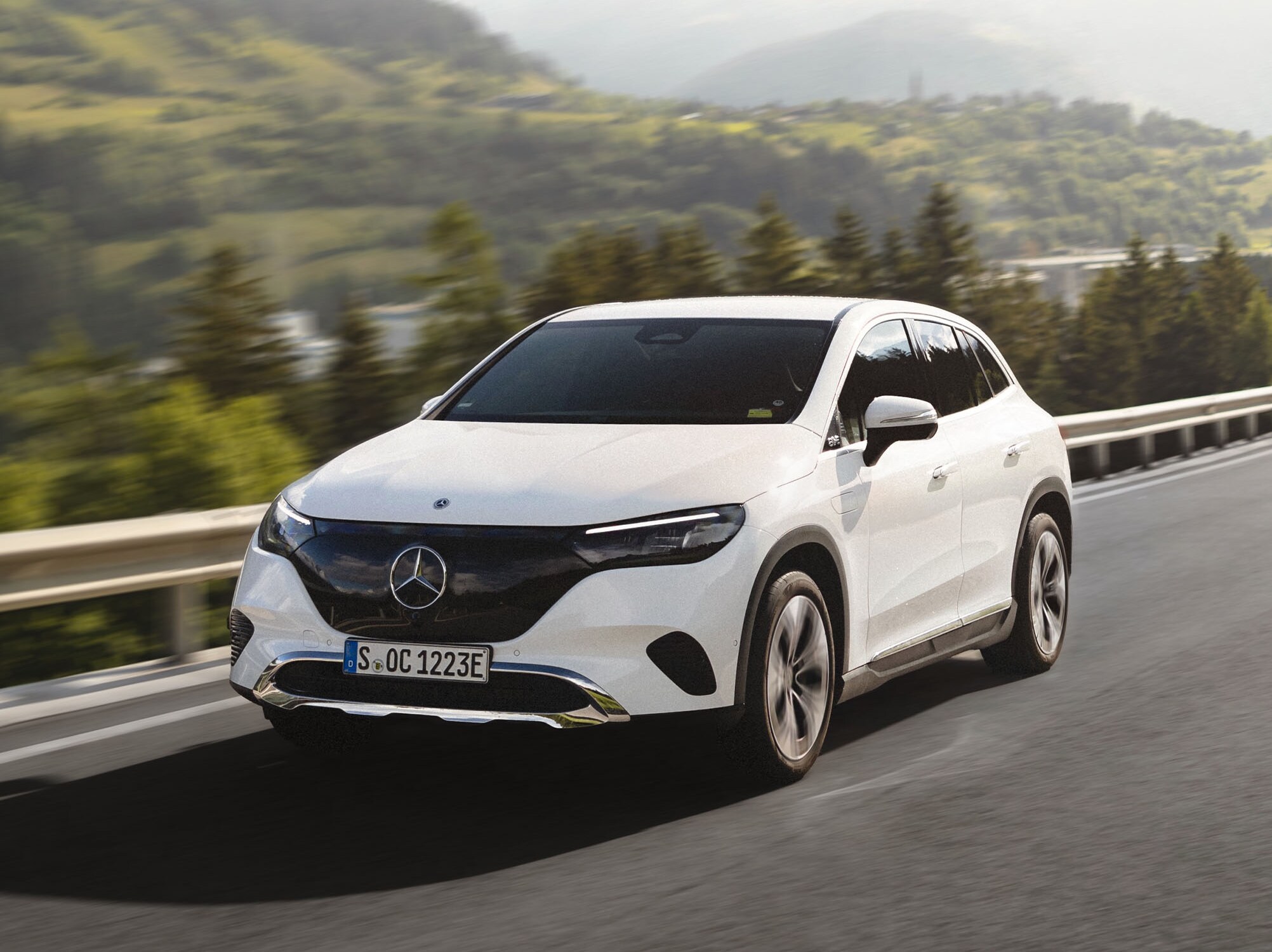Vit EQS SUV från Mercedes-Benz kör på en bergsväg.