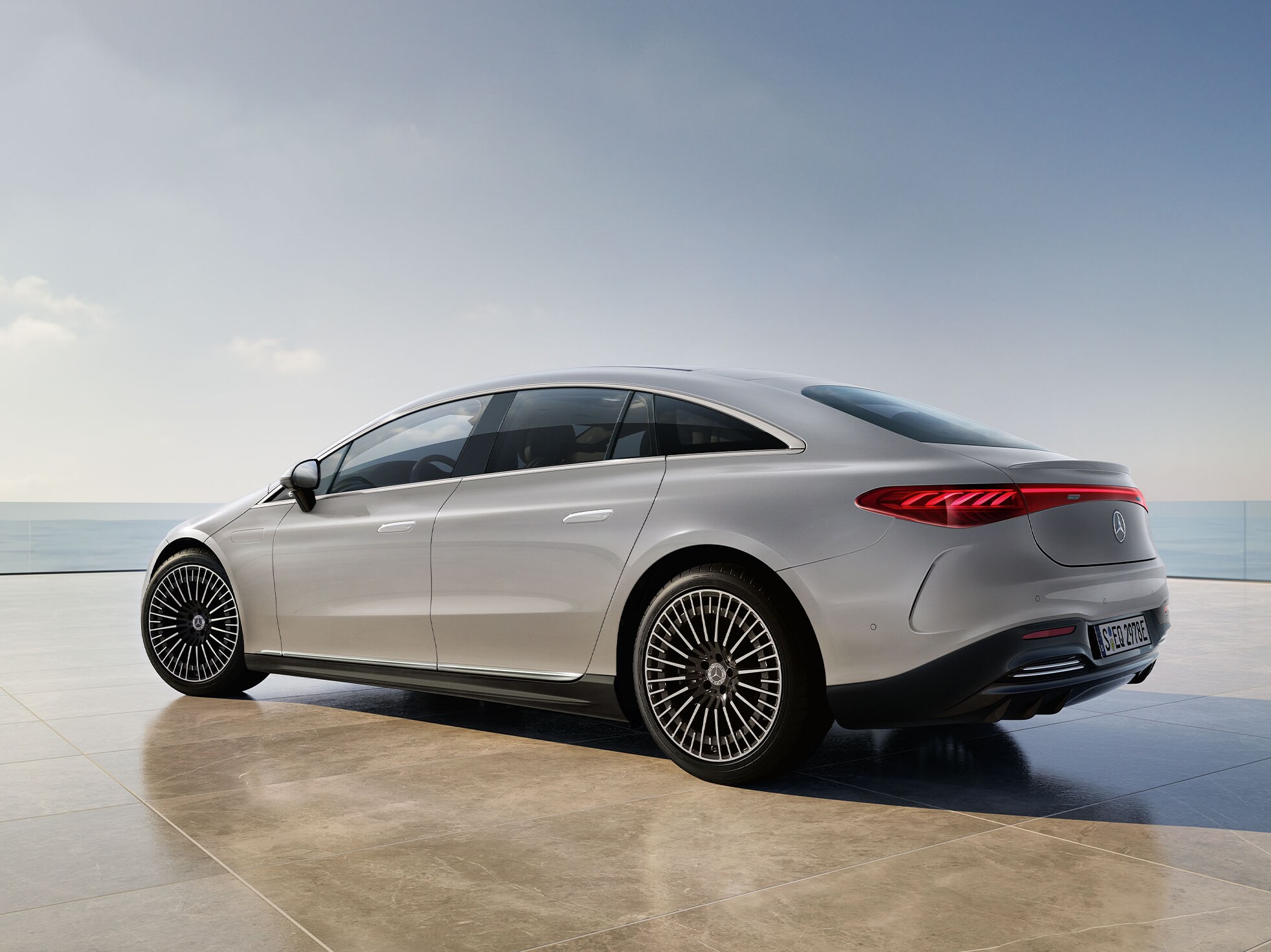 Vit EQS Sedan från Mercedes-Benz står med utsikt över vattnet.