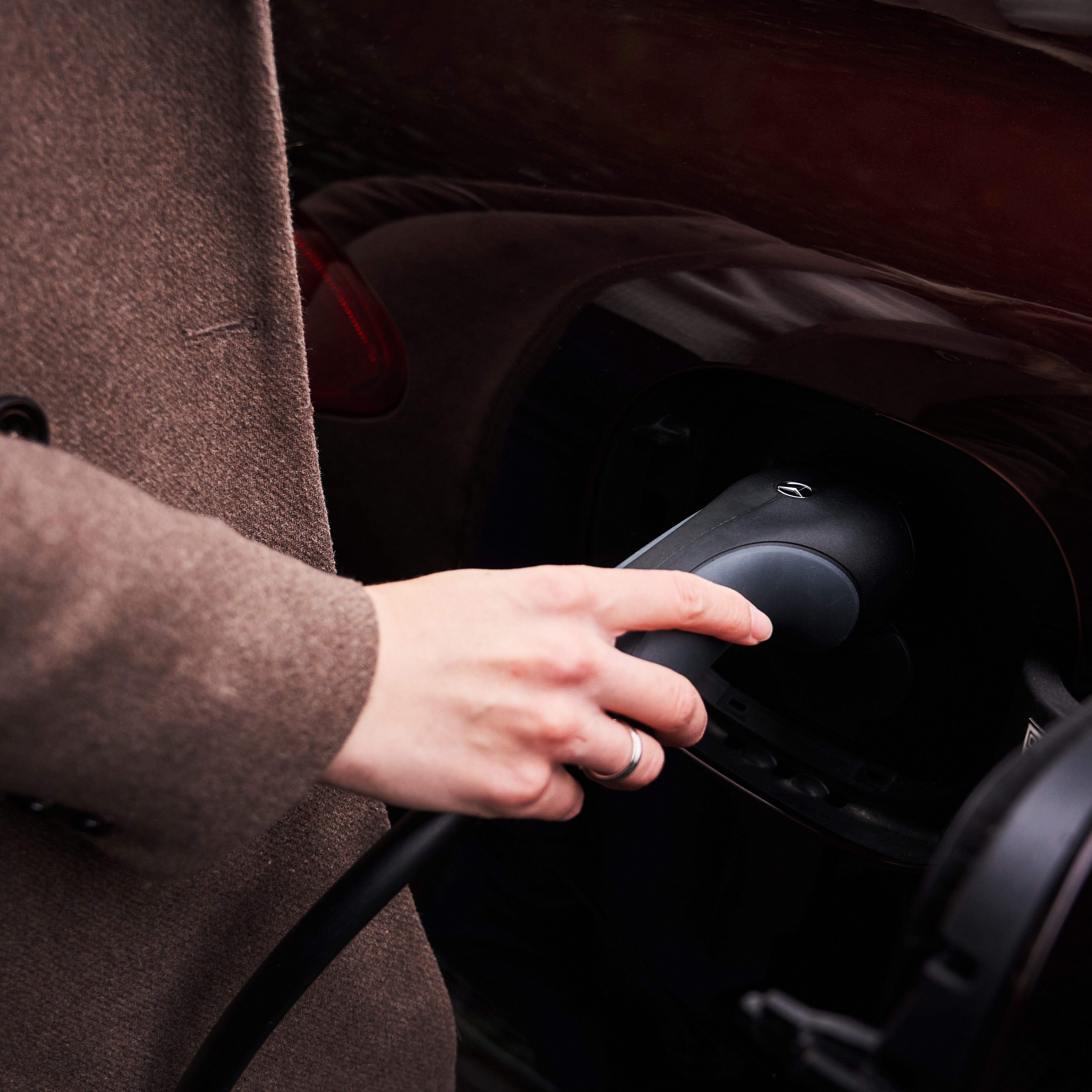 Kvinna sätter i laddkabeln i sin elektriska Mercedes-Benz.
