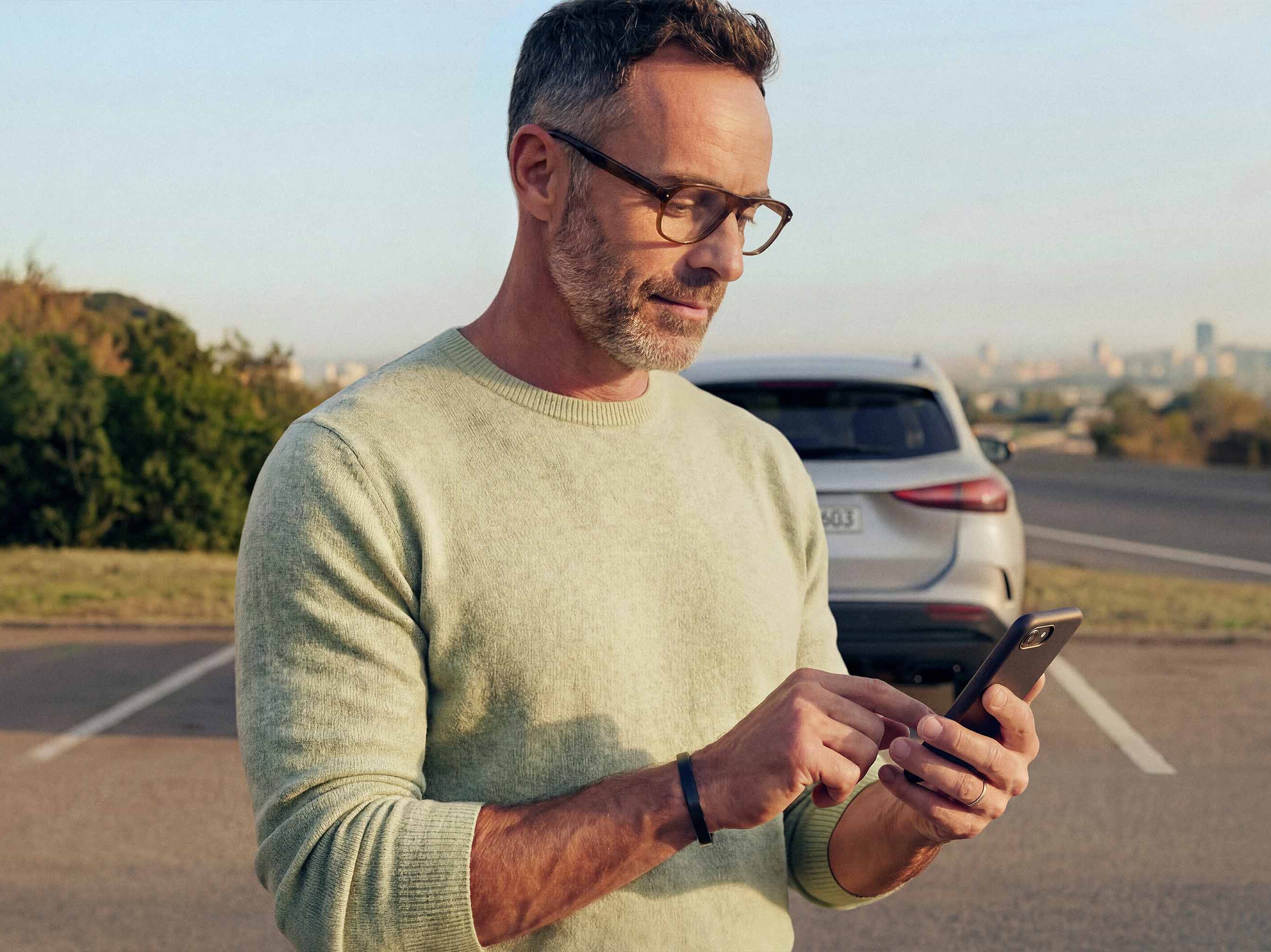 Man använder Mercedes-Benz digitala tjänster på sin mobil.