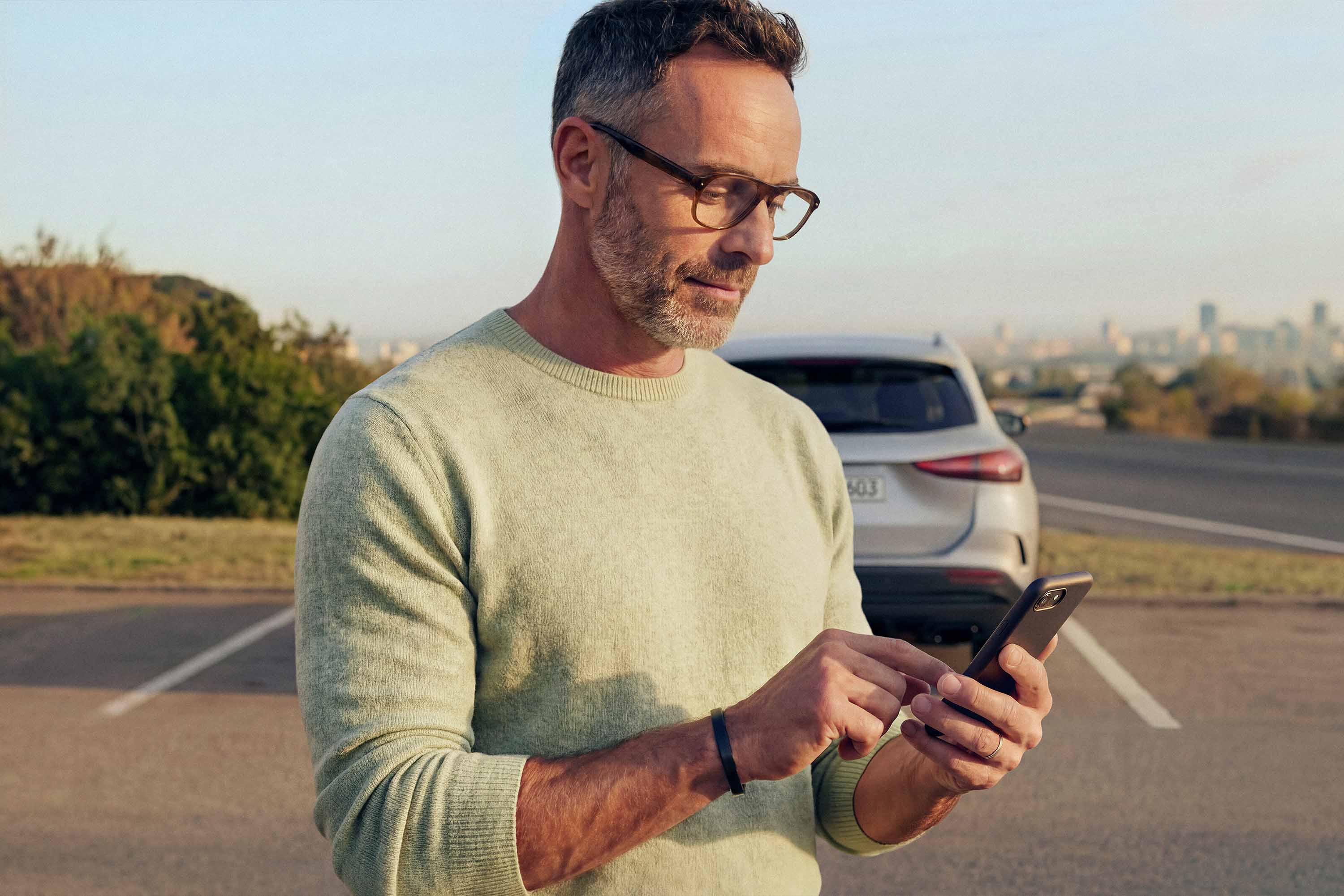 Certifierade begagnade bilar | Mercedes-Benz Man använder Mercedes-Benz digitala tjänster på sin mobil.