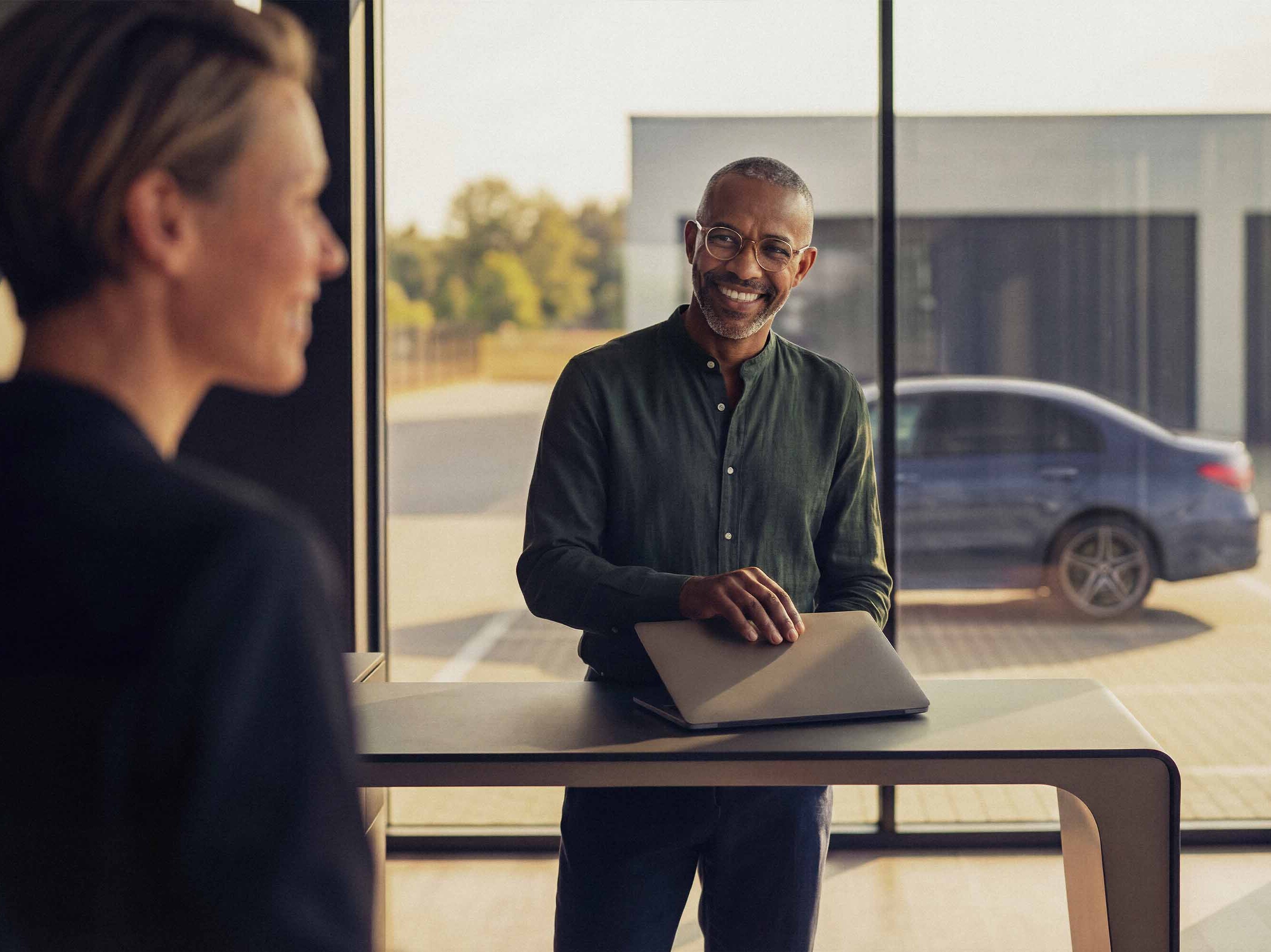 Mercedes-Benz-återförsäljare i ett showroom med en kund som ska titta på en begagnad bil.