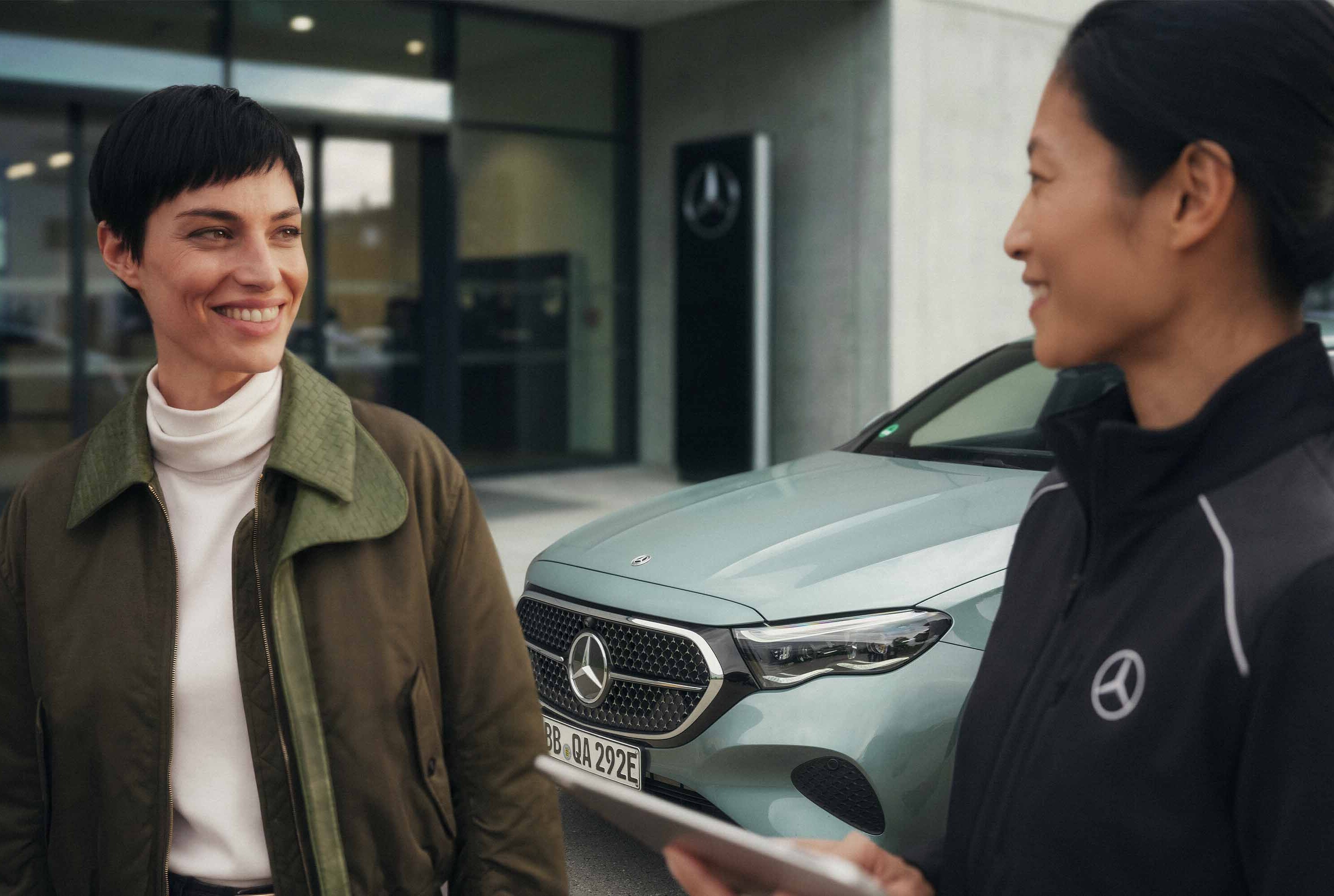 Mercedes-Benz-återförsäljare pratar med en kund utanför ett showroom.