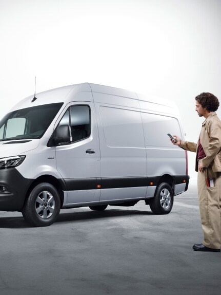 En man framför en vit Mercedes-Benz eSprinter.