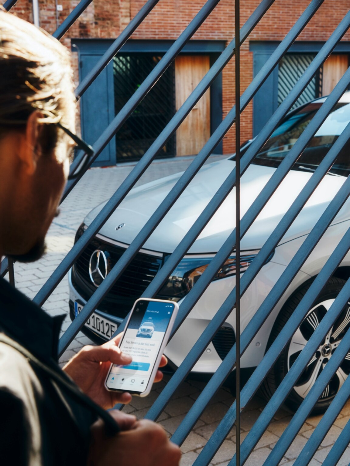 Man står framför sin Mercedes-Benz SUV och använder Mercedes-Benz app
