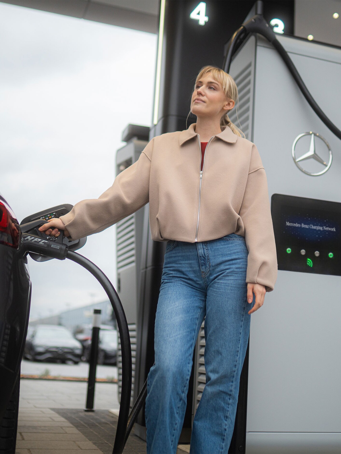 Kvinna laddar sin bil från Mercedes-Benz med hjälp av MB.CHARGE public.