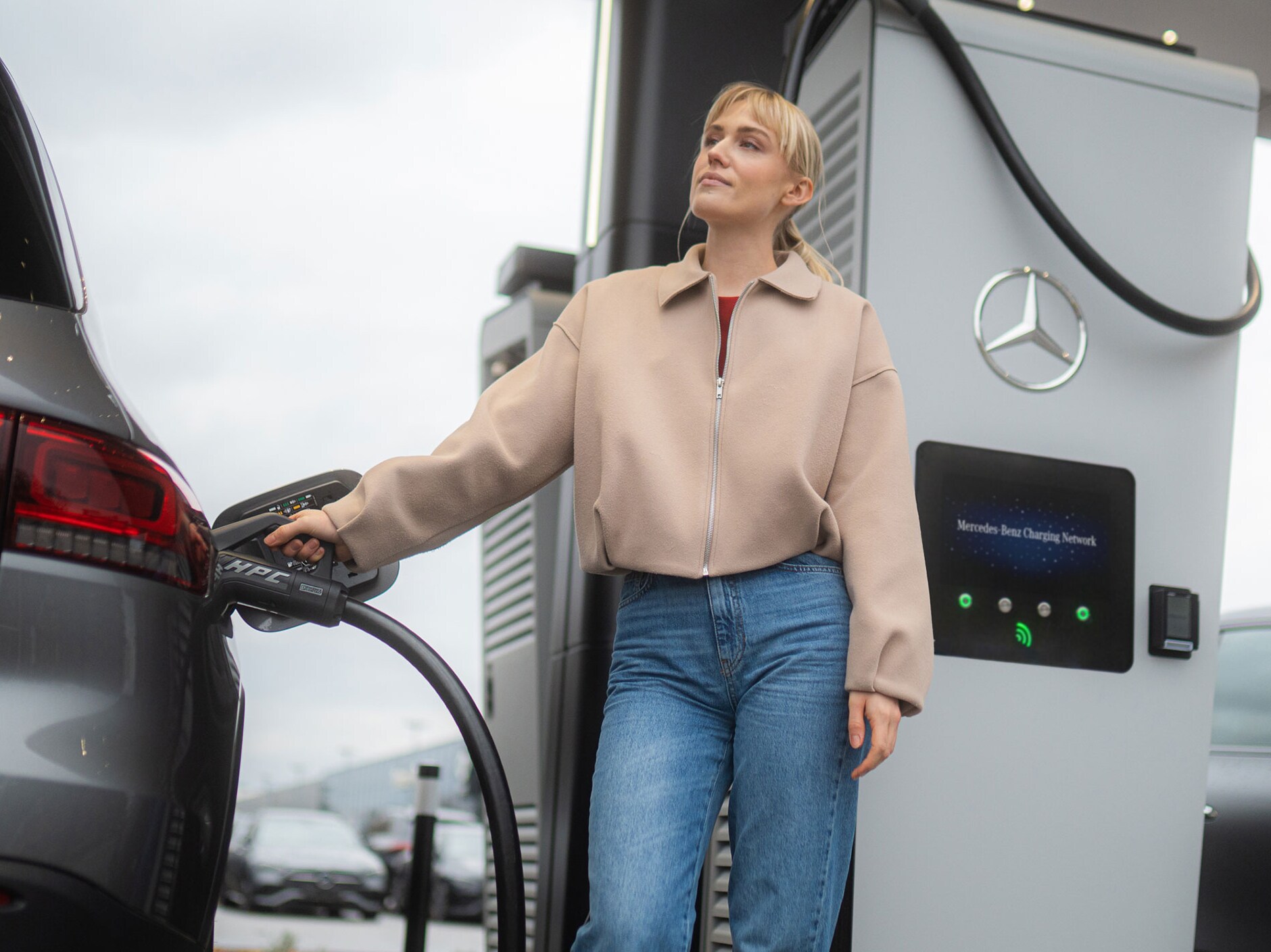 Kvinna laddar sin bil från Mercedes-Benz med hjälp av MB.CHARGE public.