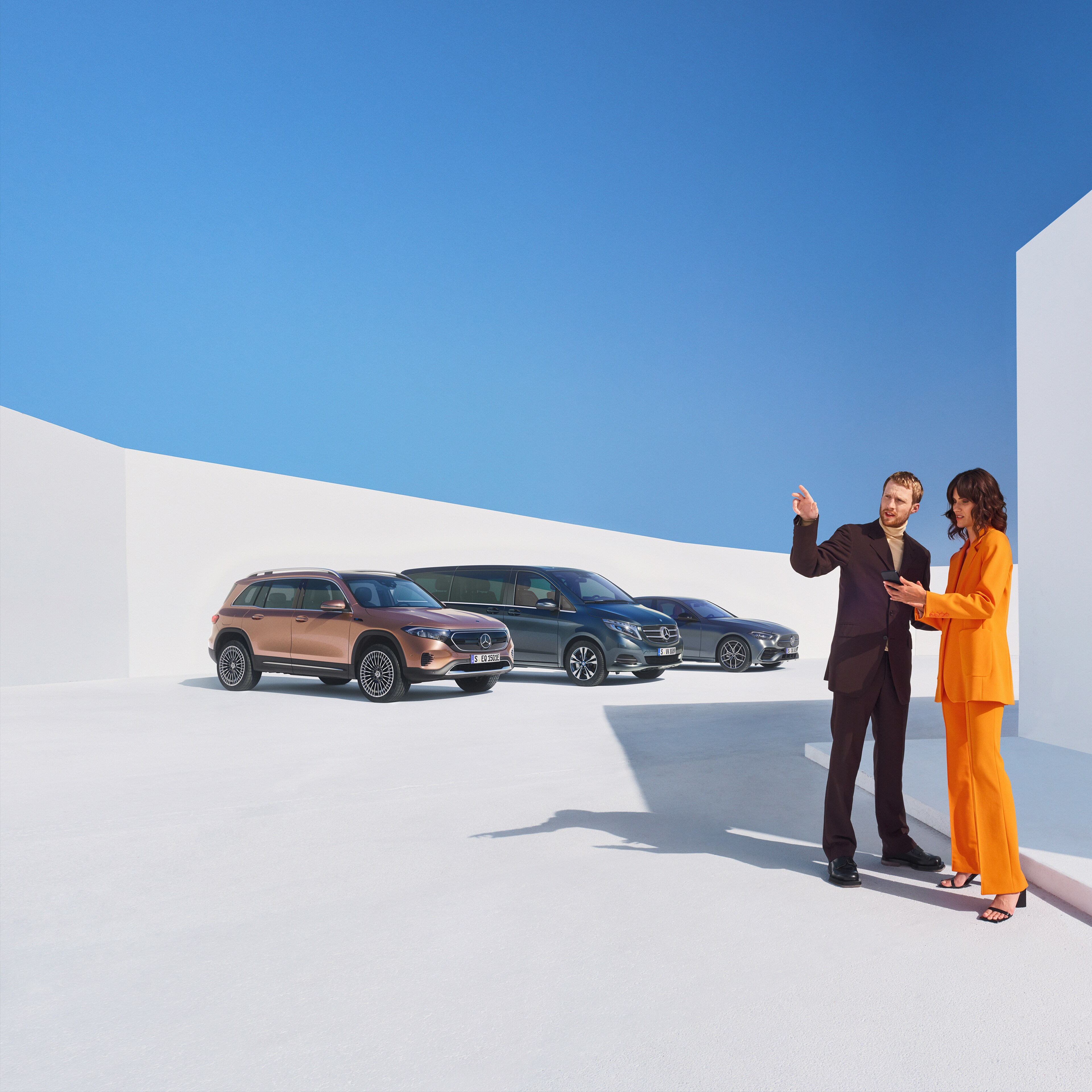 Två personer diskuterar digitala tjänster framför tre bilar från Mercedes-Benz.