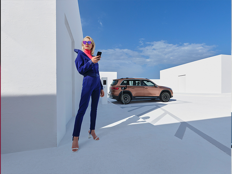 Mercedes me-appar | Digitala tjänster | Mercedes me En person använder Mercedes-Benz app medan elbilen EQB laddas i bakgrunden.