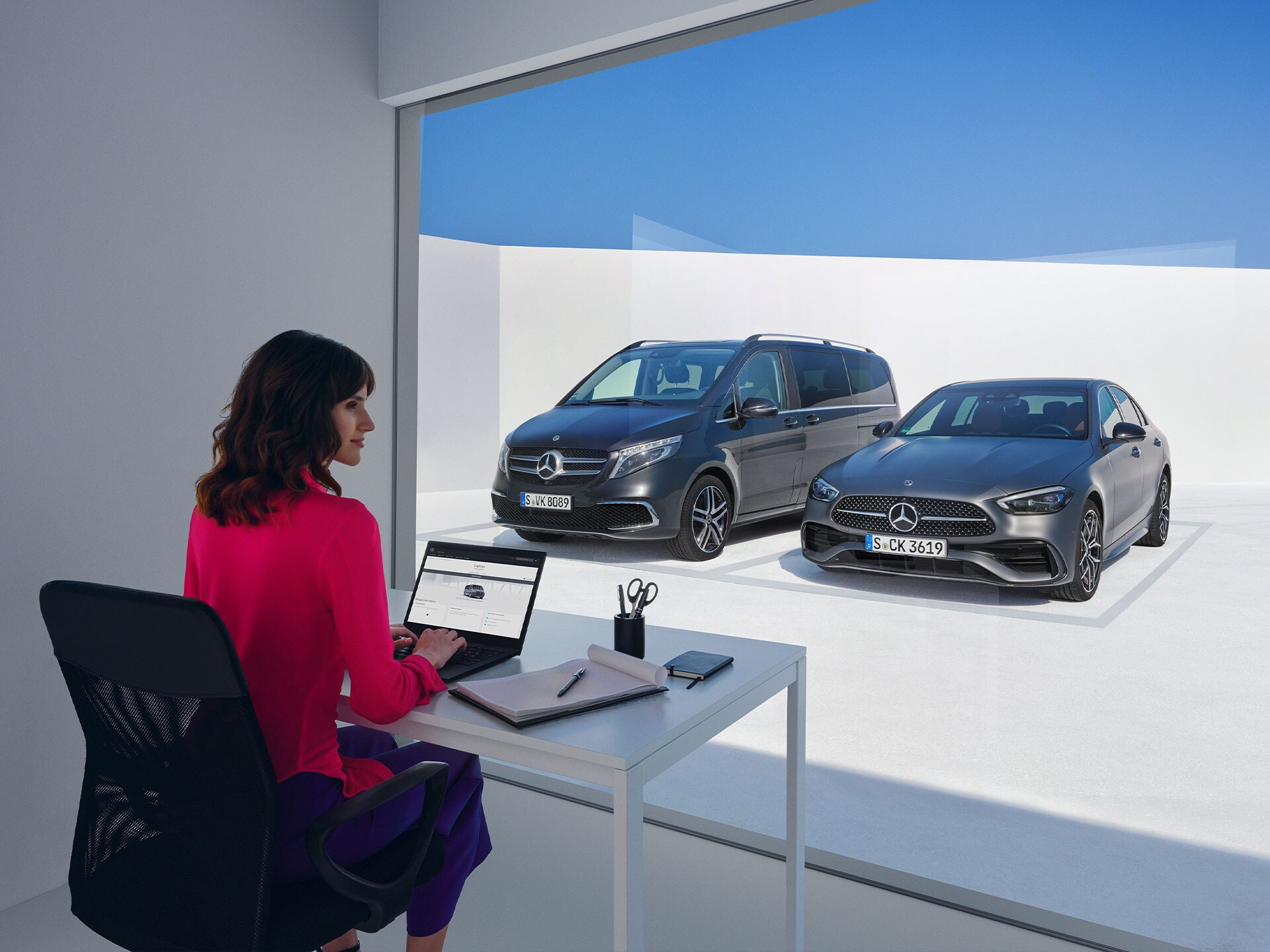 Kvinna arbetar på kontor med utsikt över en skåpbil och en personbil från Mercedes-Benz.