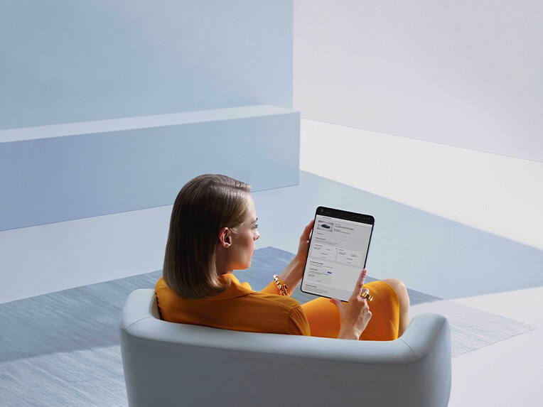 Kvinna använder en surfplatta för att se bilens status via Mercedes-Benz app.