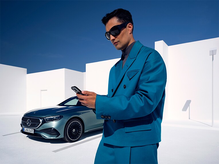 Man får fjärrdiagnos om sin Mercedes-Benz status via smartphone framför sin bil.
