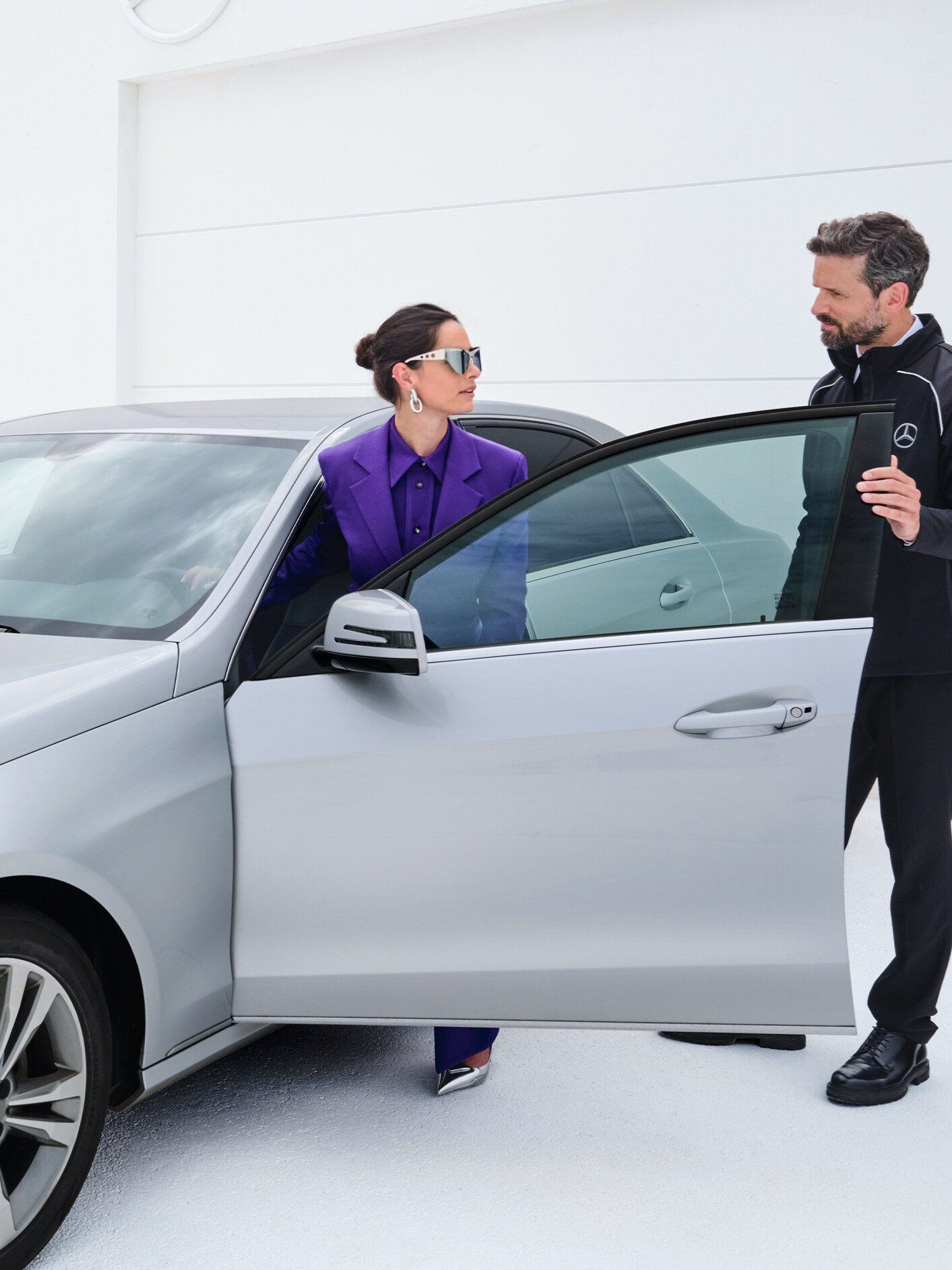 Kvinna stiger in i sin bil medan hon pratar med Mercedes-Benz servicemedarbetare