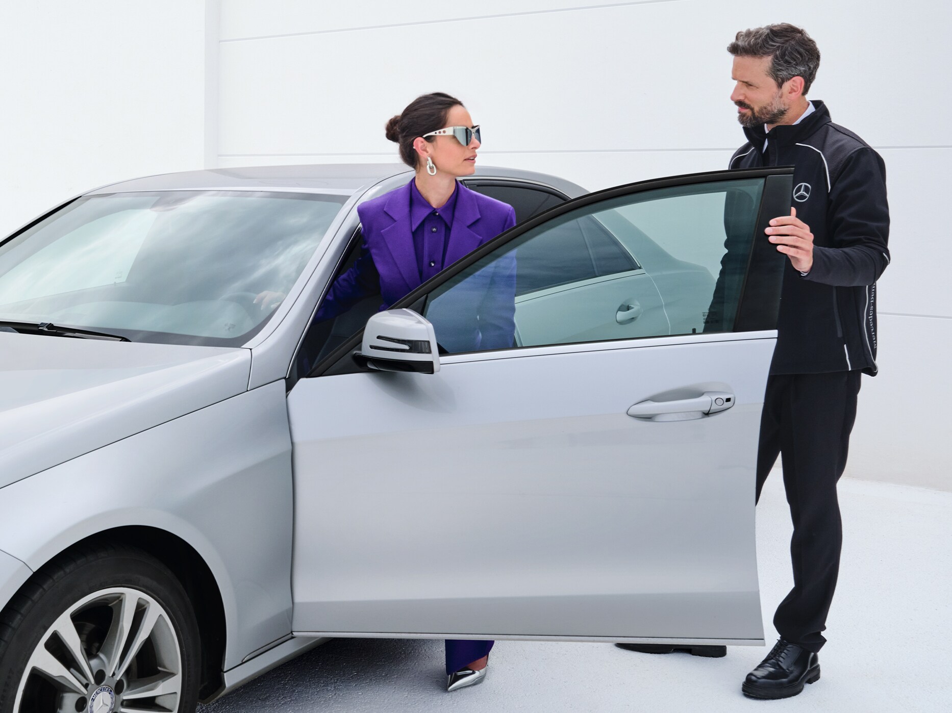 Kvinna stiger in i sin bil medan hon pratar med Mercedes-Benz servicemedarbetare