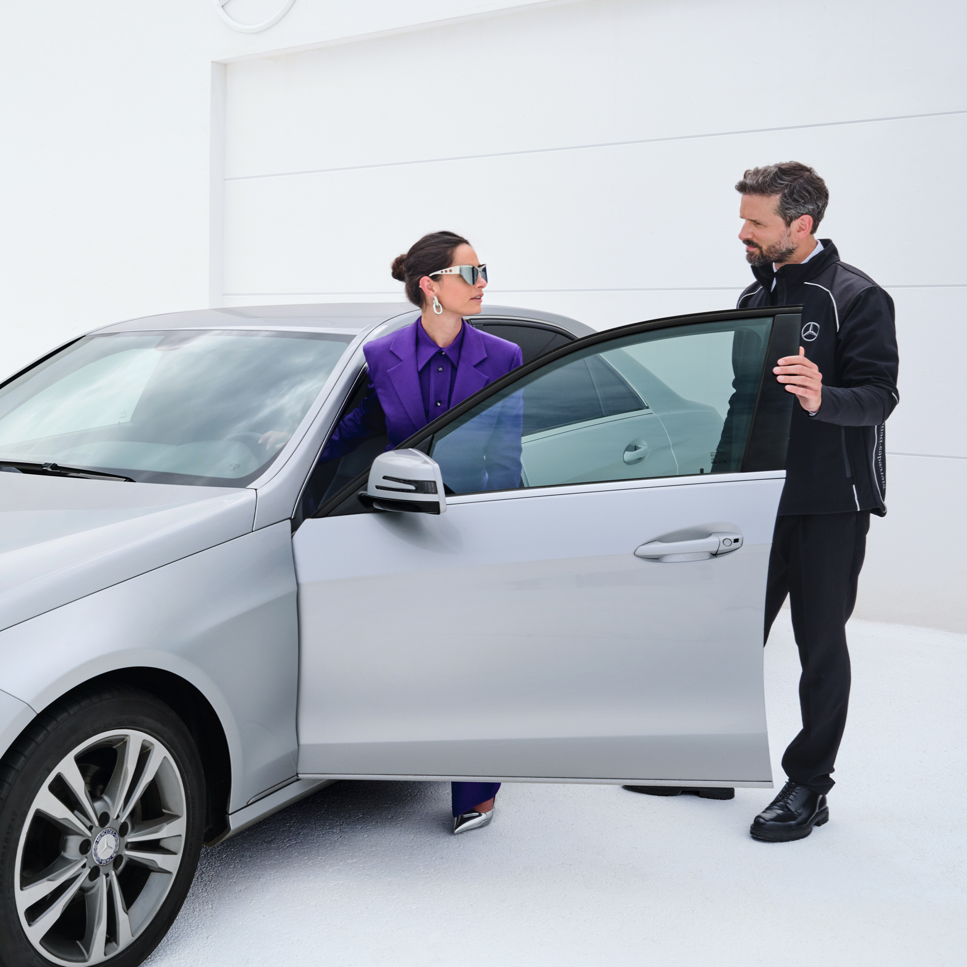 Nedstängning av Service appen | Service appen | Mercedes-Benz digitala tjänster Kvinna stiger in i sin bil medan hon pratar med Mercedes-Benz servicemedarbetare