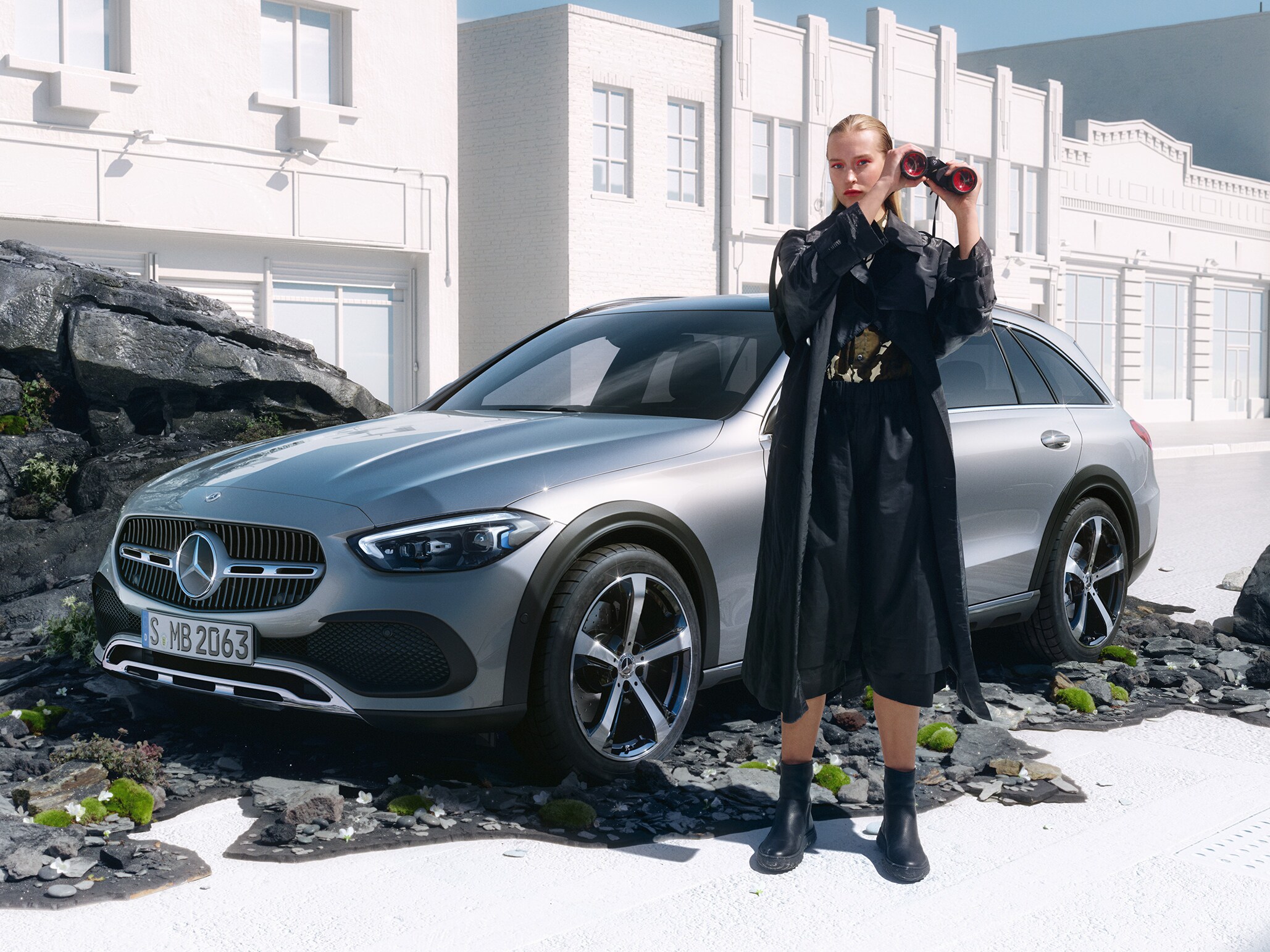Kvinna med kikare står framför C-Klass Kombi från Mercedes-Benz.
