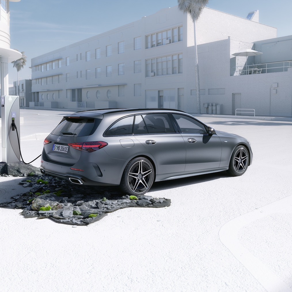 Dynamisk vy av en Mercedes-Benz C-Klass Kombi (körbild) eller stående vid en laddningsstation.