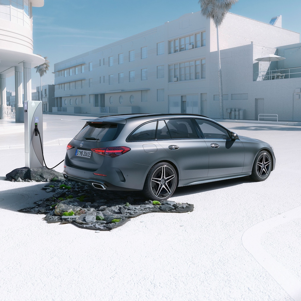 Dynamisk vy av en Mercedes-Benz C-Klass Kombi (körbild) eller stående vid en laddningsstation.
