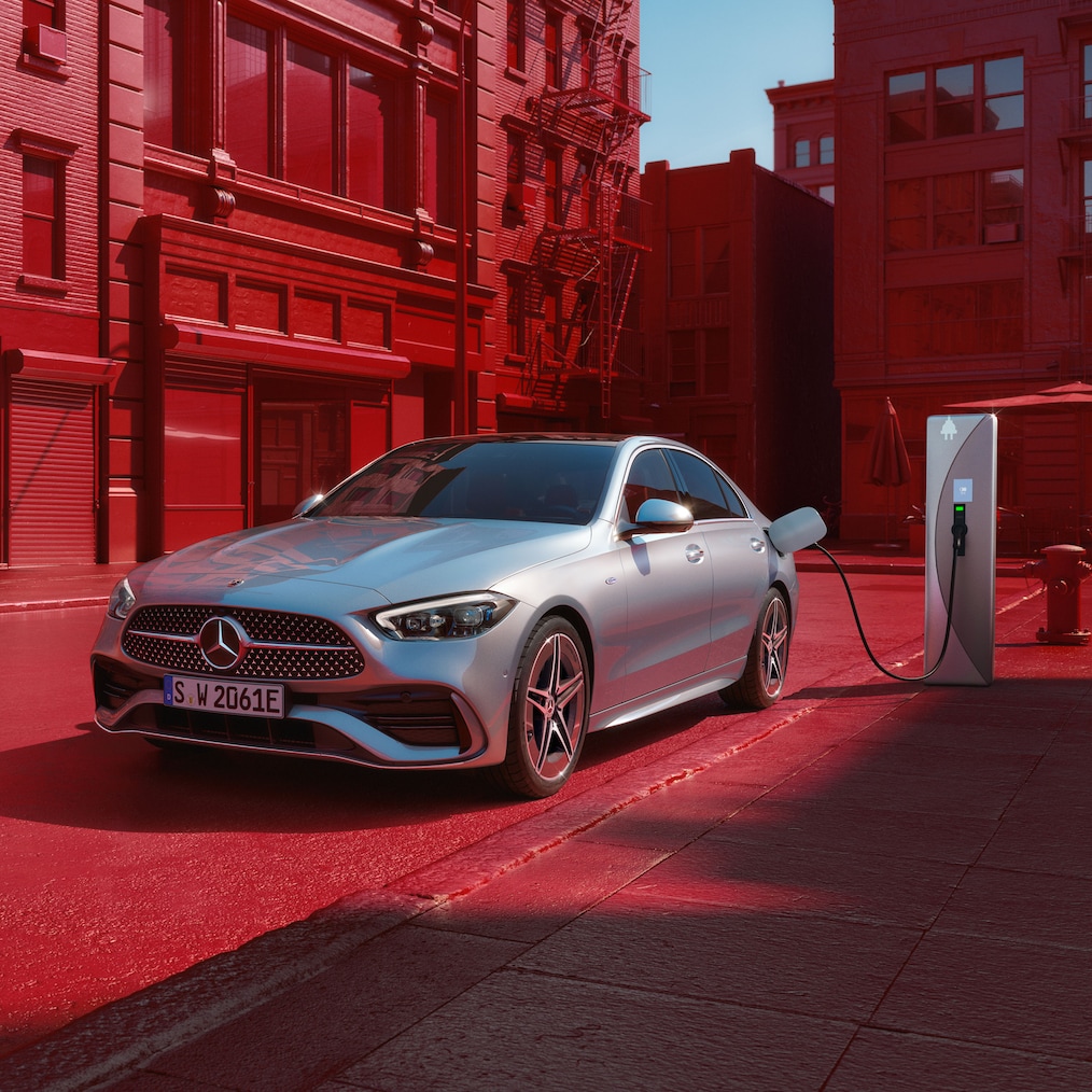 Dynamisk vy av en Mercedes-Benz C-Klass Sedan (körbild) eller stående vid en laddningsstation.