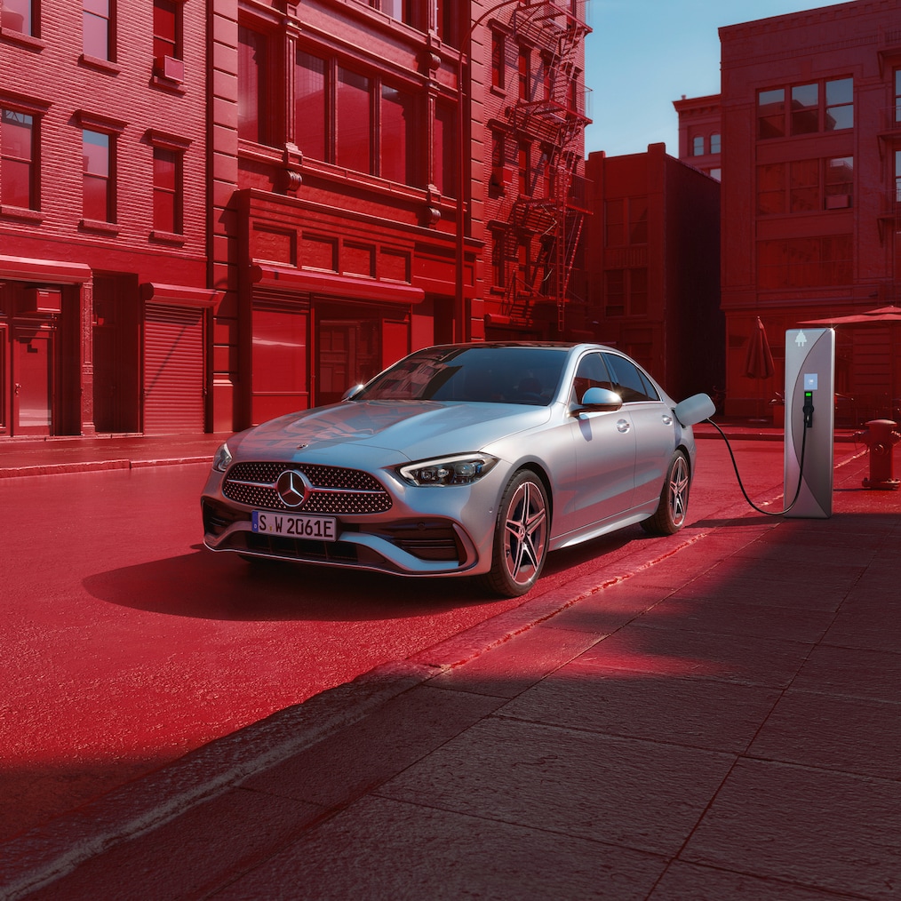 Dynamisk vy av en Mercedes-Benz C-Klass Sedan (körbild) eller stående vid en laddningsstation.