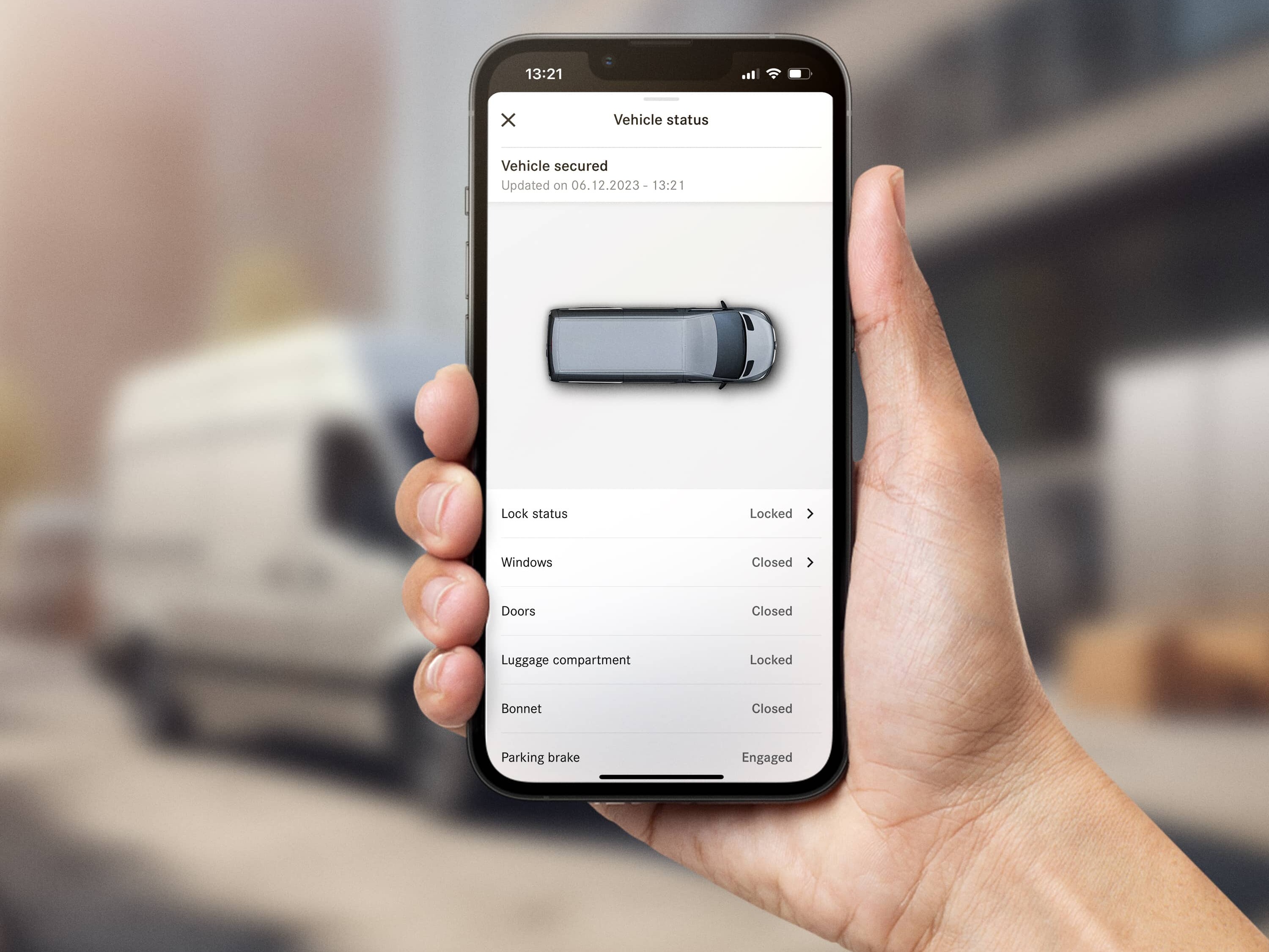 Person håller smartphone med Mercedes-Benz app, Vito i bakgrunden