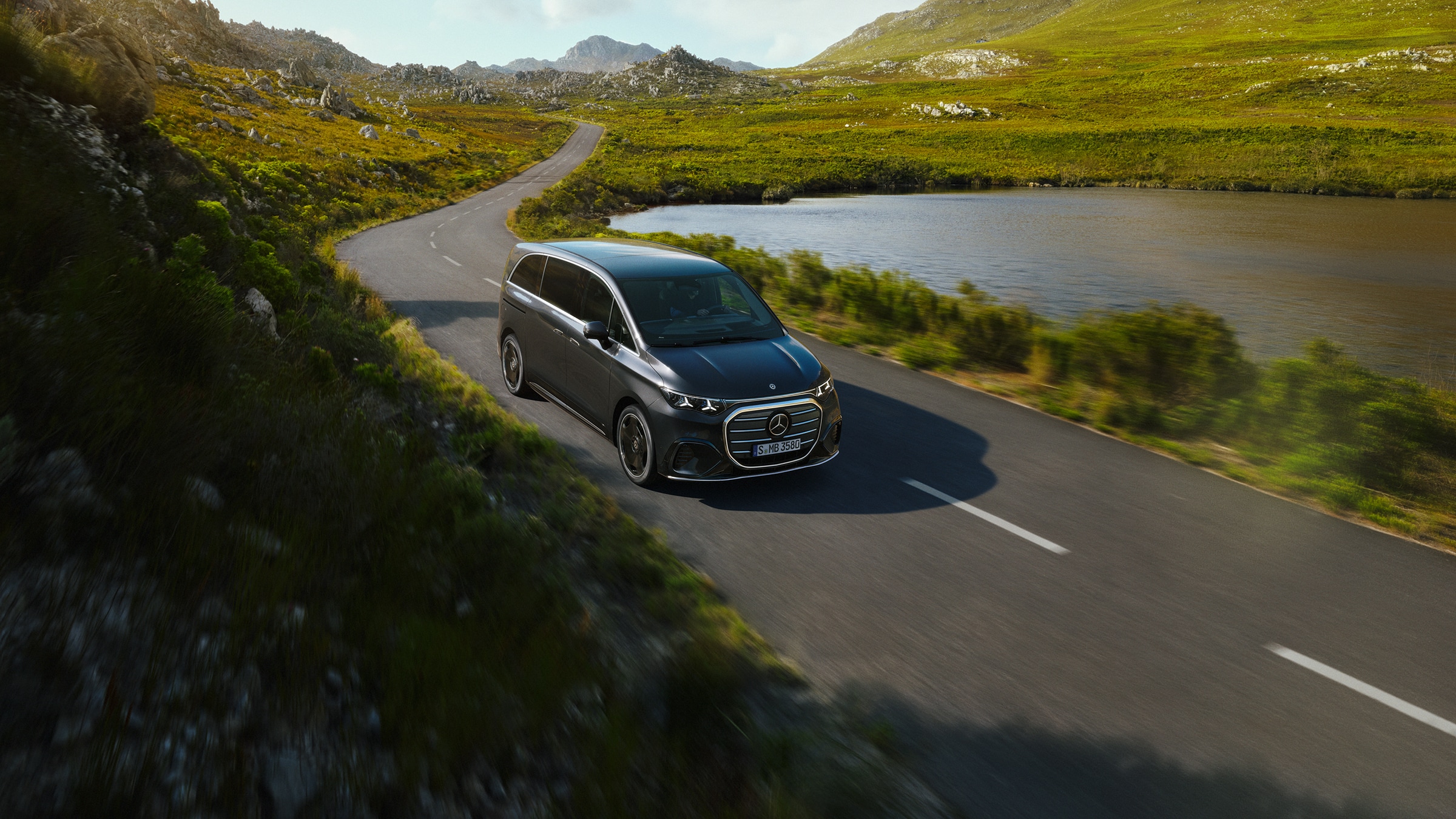 VLE | Transportbils- och campingbilsmodeller | Mercedes-Benz transportbilar Mercedes-Benz VLE kör längs en naturskön väg vid en sjö och visar förstklassig komfort, rymlighet och förfinad mångsidighet för resor.