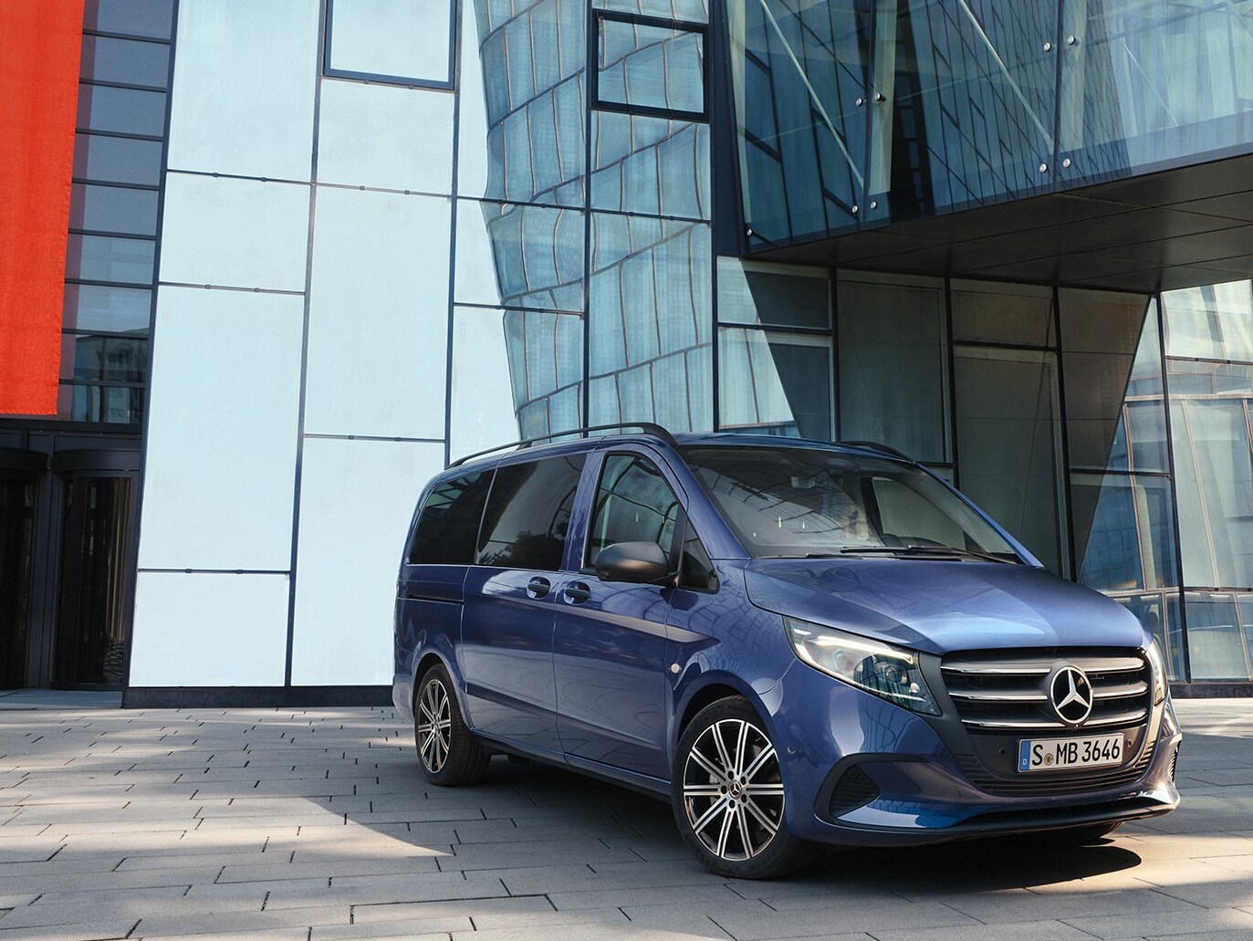 Mercedes-Benz Vito Tourer med skjutdörr framför en modern byggnad.