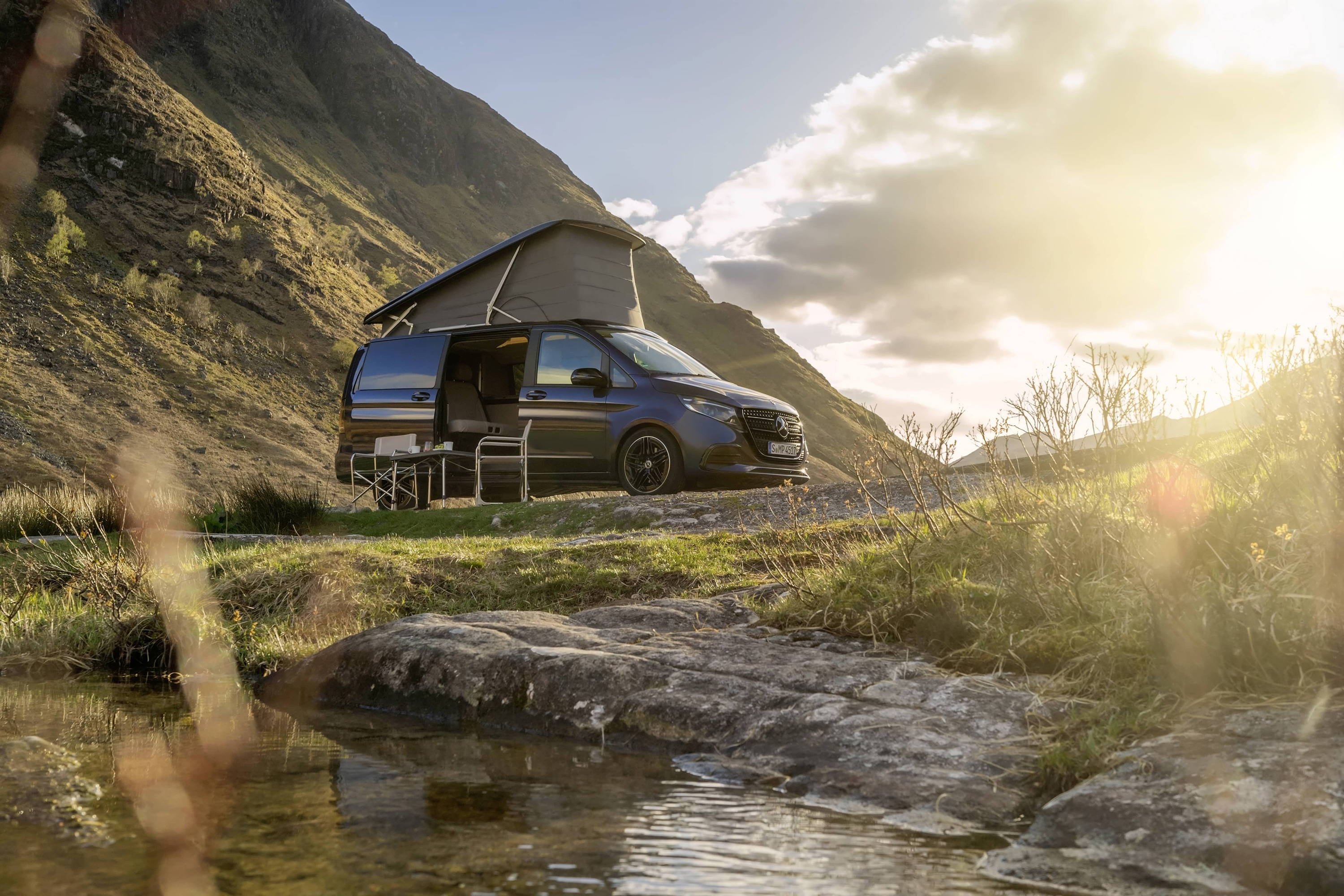 Marco Polo | Sprinter Camper Vans | Mercedes-Benz Mercedes-Benz Marco Polo-camper med pop-up-tak i ett naturskönt bergslandskap som visar friluftsäventyr och vanlife-frihet.