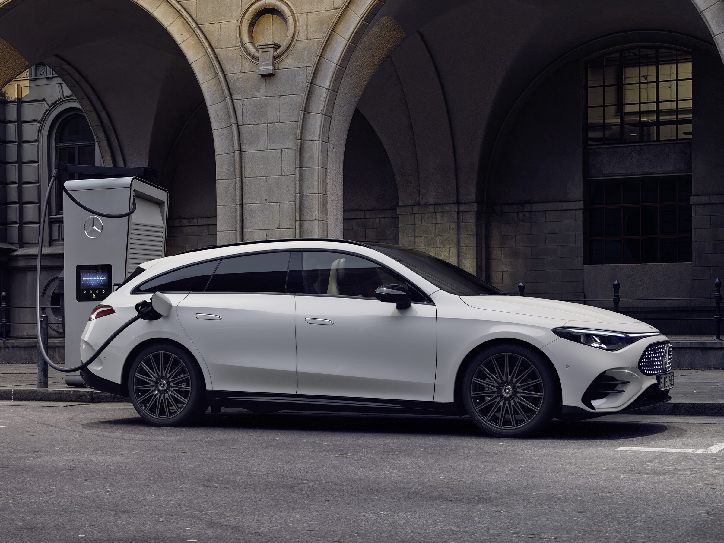 Vit Mercedes-Benz CLA laddas vid en offentlig laddstation.