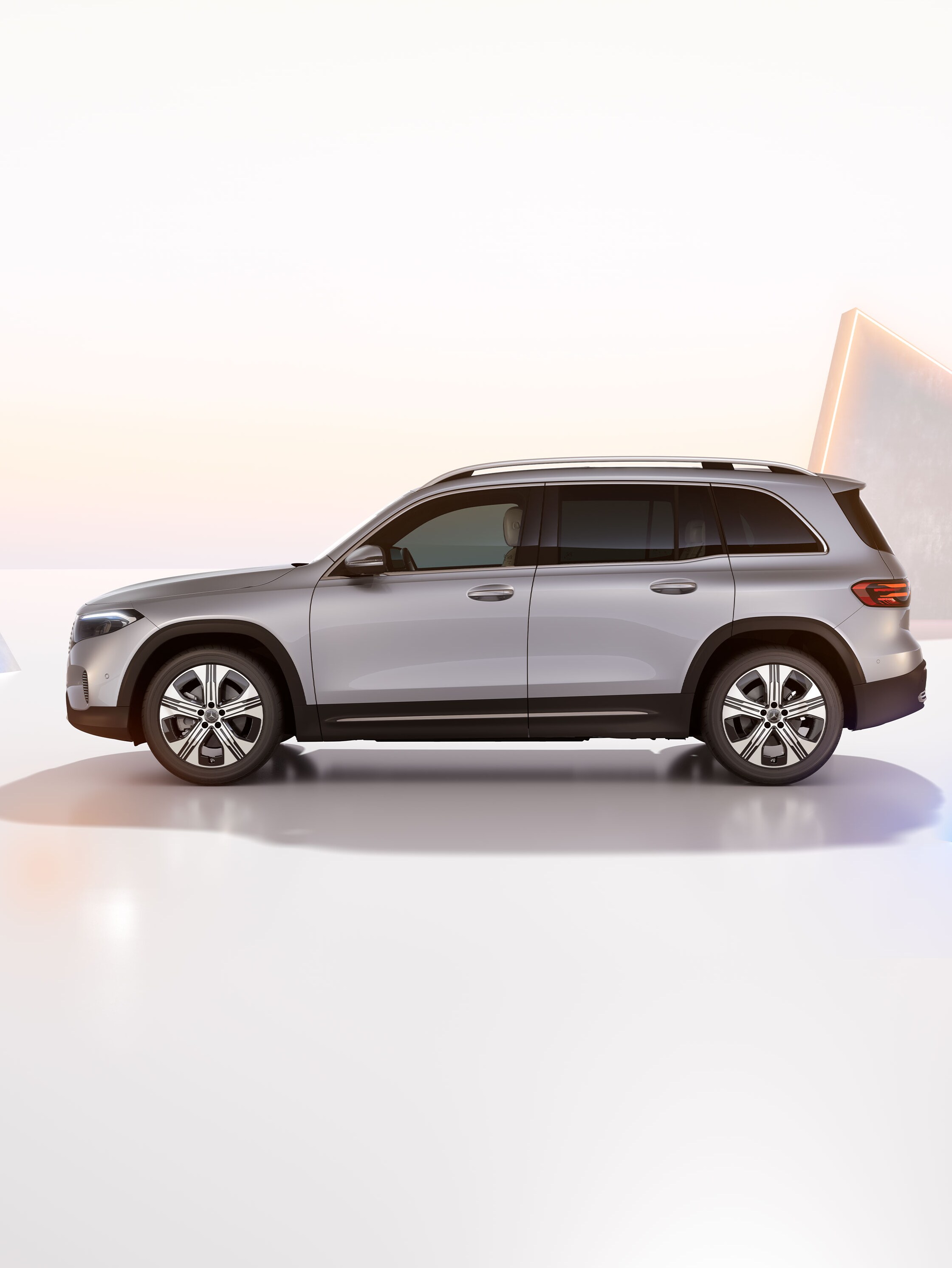 Ljusgrå Mercedes-Benz EQB sidovy mot konstfull bakgrund