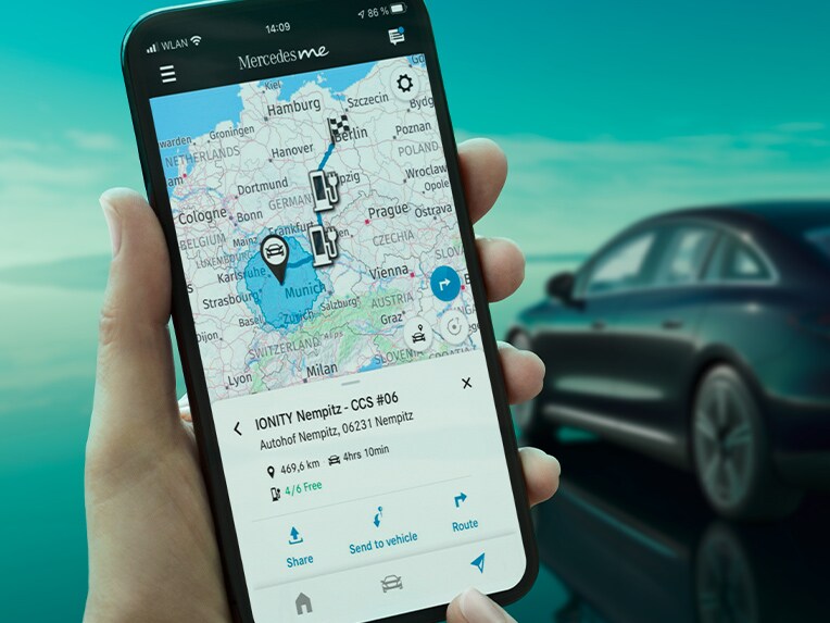 Appen Mercedes-Benz ECO Coach på en smartphone och i bakgrunden EQE Sedan som laddas vid en väggmonterad laddbox.
