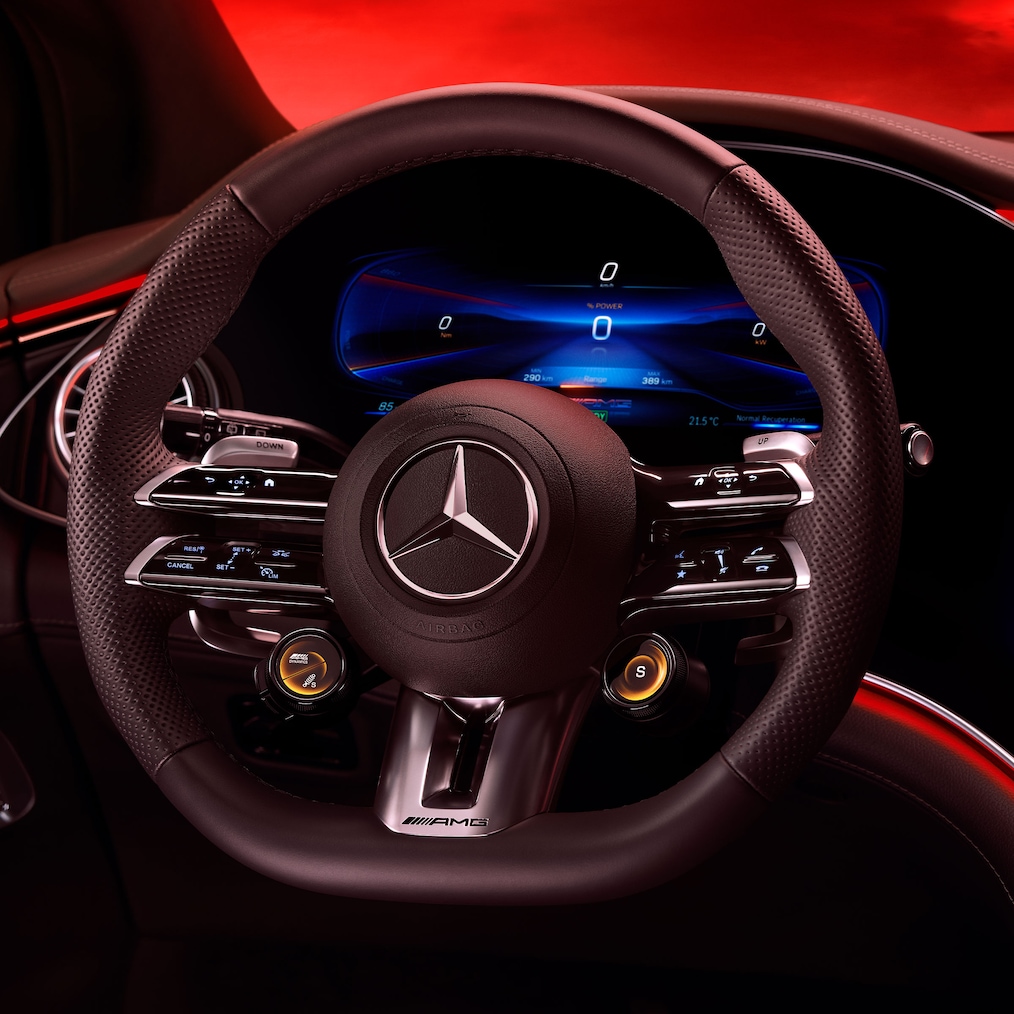 Vy över AMG Performance-ratten, sedd från förarsätet mot en röd bakgrund.