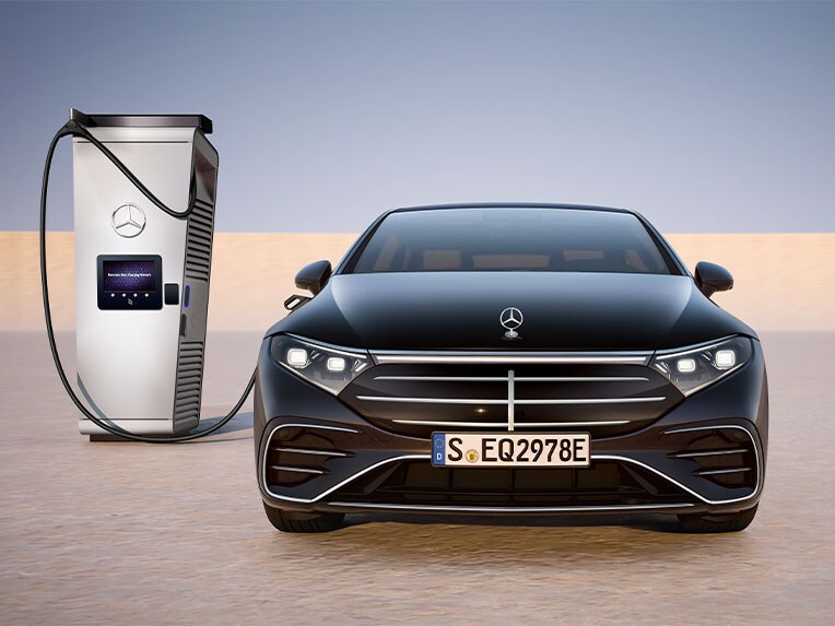 En EQS Sedan från Mercedes-Benz, sedd framifrån, laddas vid en offentlig laddningsstation.