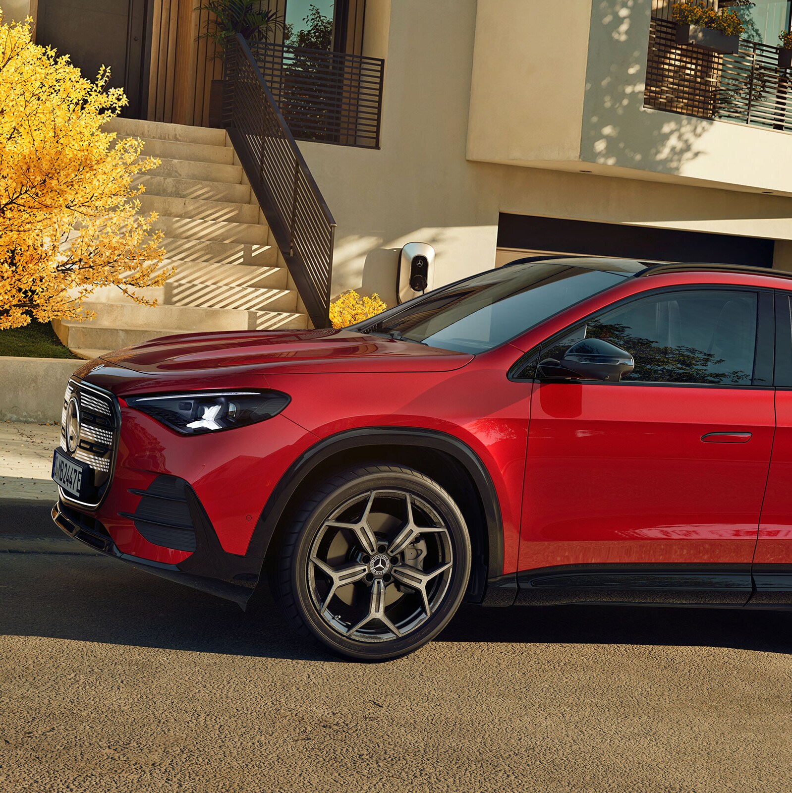 Röd eldriven Mercedes-Benz GLA parkerad på en bostadsgata framför ett hus
