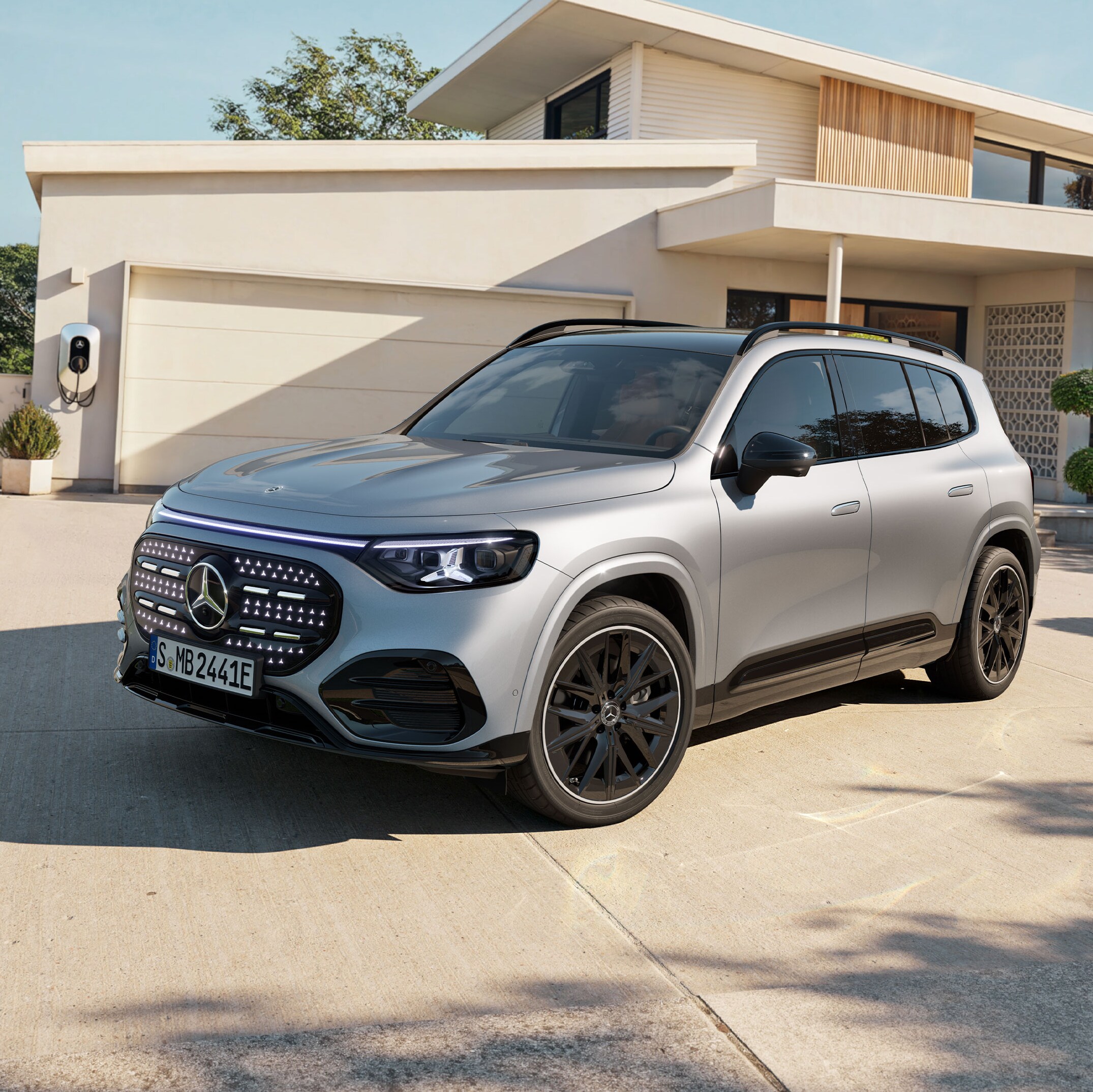 Silverfärgad Mercedes-Benz GLB med EQ-teknik framför huset med garage
