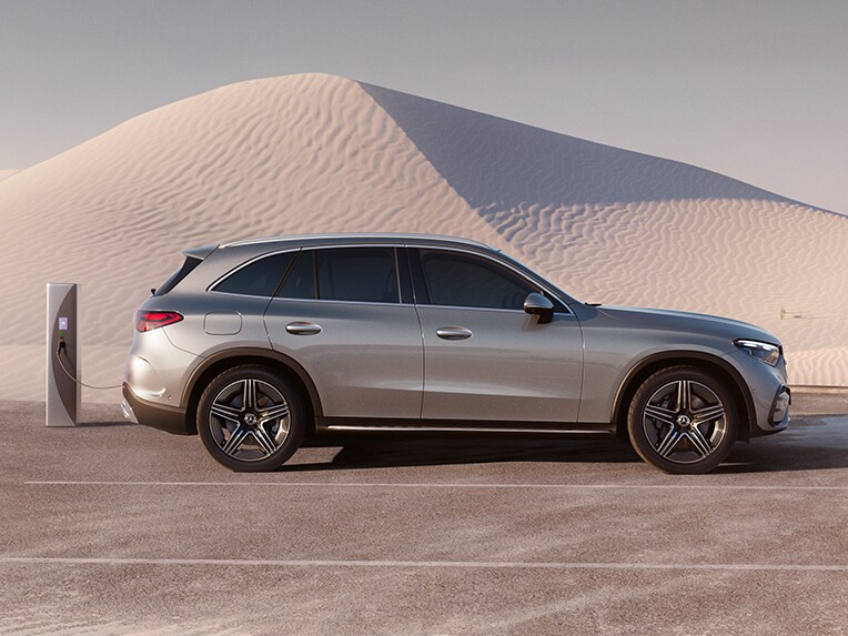 En silvrig Mercees-Benz SUV laddas vid laddstolpe