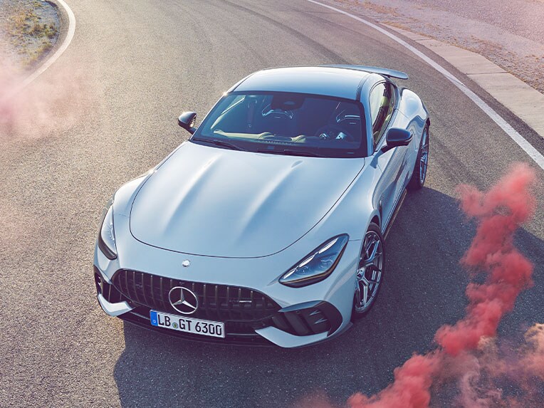 Mercedes-AMG-bil kör på racerbana omgiven av röd rök