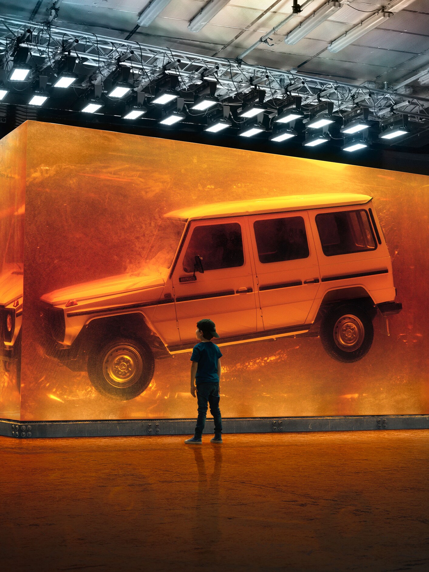 Pojke tittar på svävande Mercedes-Benz G-Klass utställd i glas