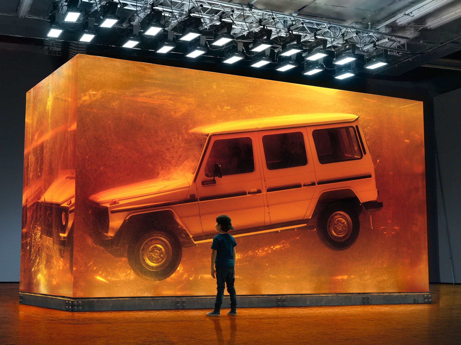 Pojke tittar på svävande Mercedes-Benz G-Klass utställd i glas.