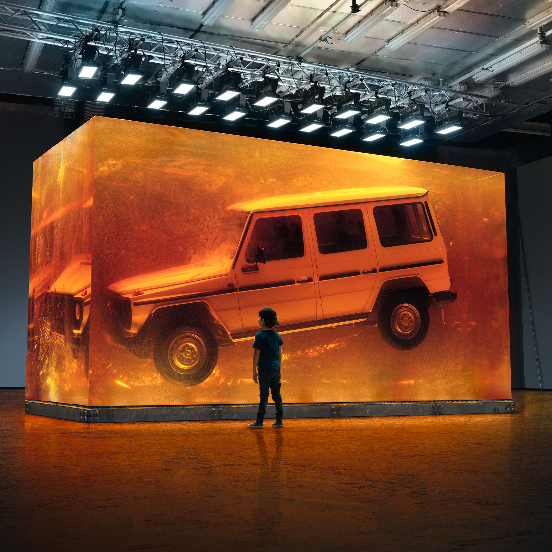 Arv | G-Klass Brand Area | Mercedes-Benz Pojke tittar på svävande Mercedes-Benz G-Klass utställd i glas.