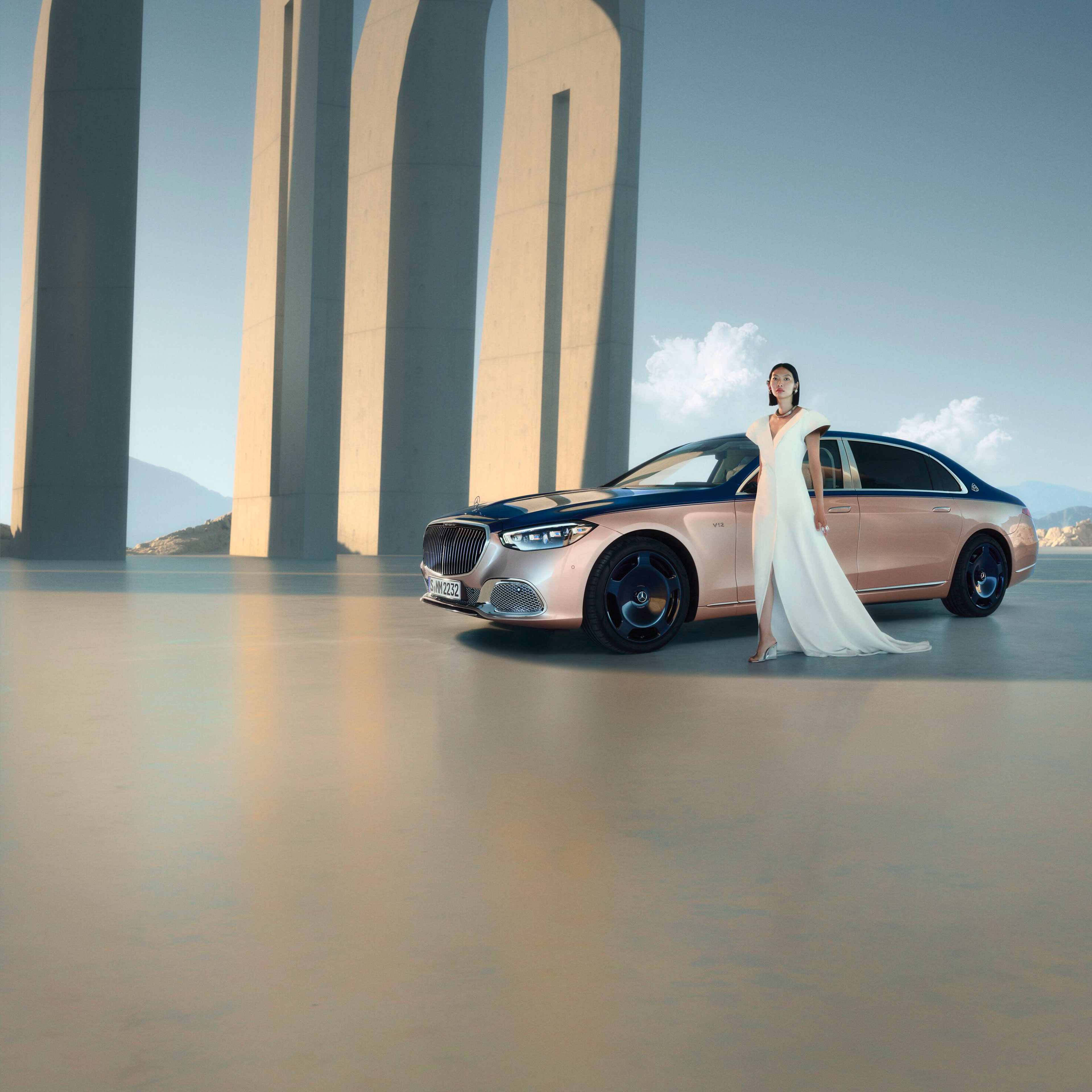 Kvinna i vit klänning framför tvåfärgad Mercedes-Maybach.