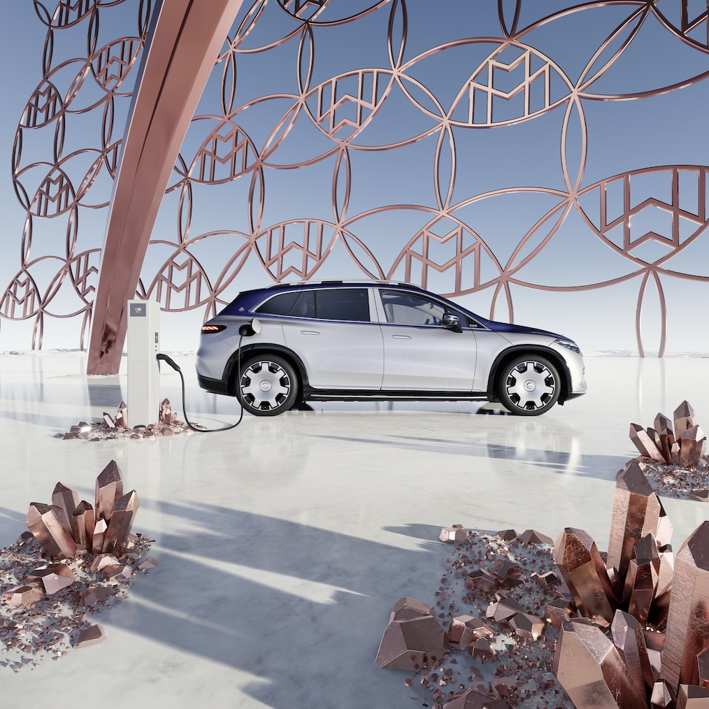 Sidovy av Mercedes-Maybach EQS Suv vid en laddningsstation, med Maybachs märkeslogotyp i bakgrunden.