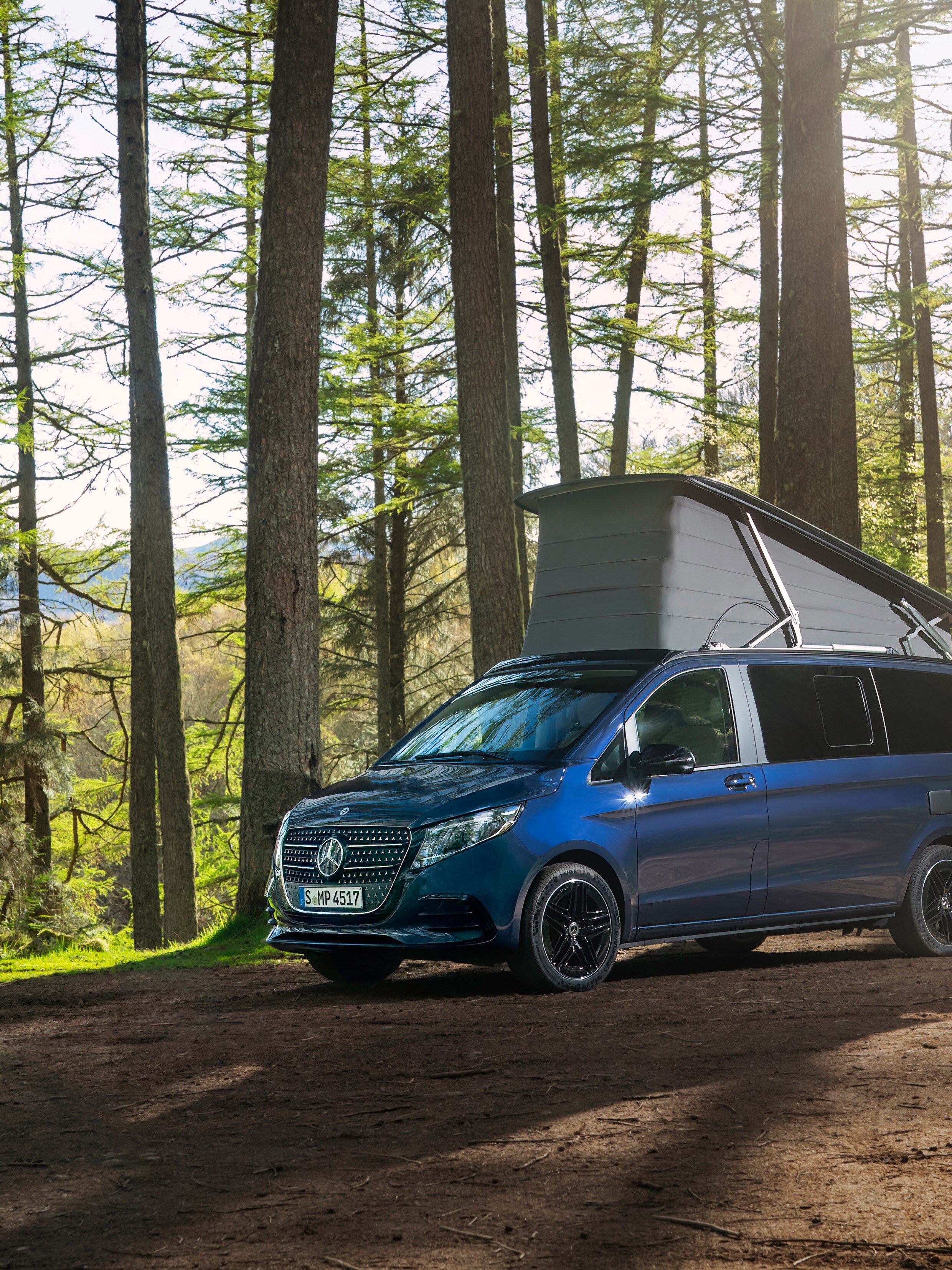 Blå Mercedes-Benz Marco Polo med uppfällt pop-up tak i skog