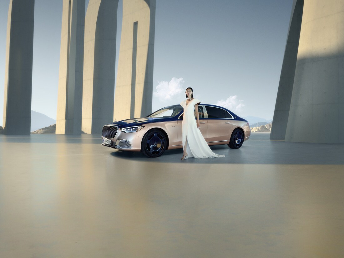 Kvinna i vit klänning framför tvåfärgad Mercedes-Maybach-bil