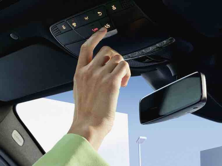 Knappen i takkontrollpanelen i en Mercedes-Benz trycks in.
