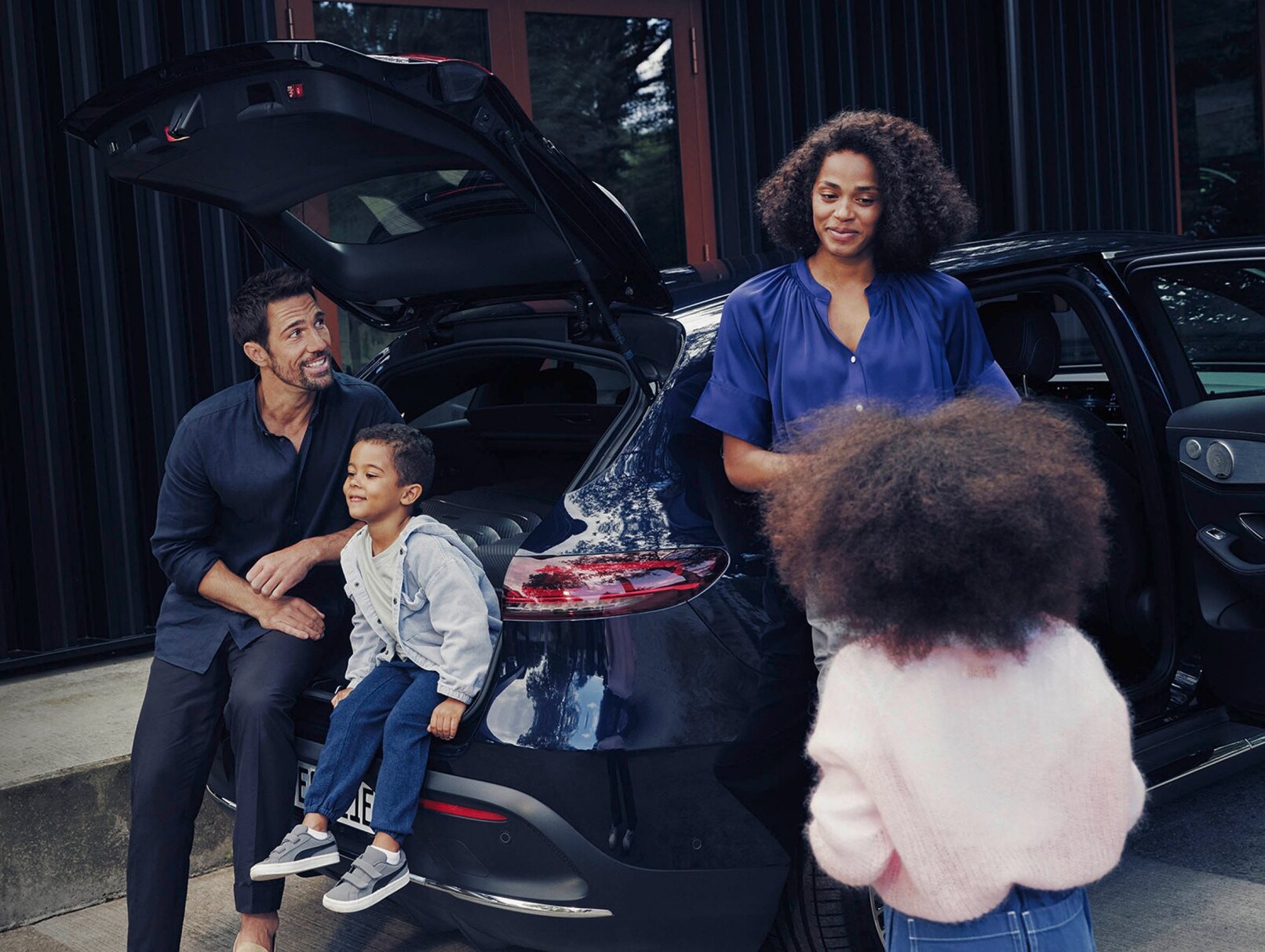 En familj sitter samlade kring en Mercedes-Benz SUV