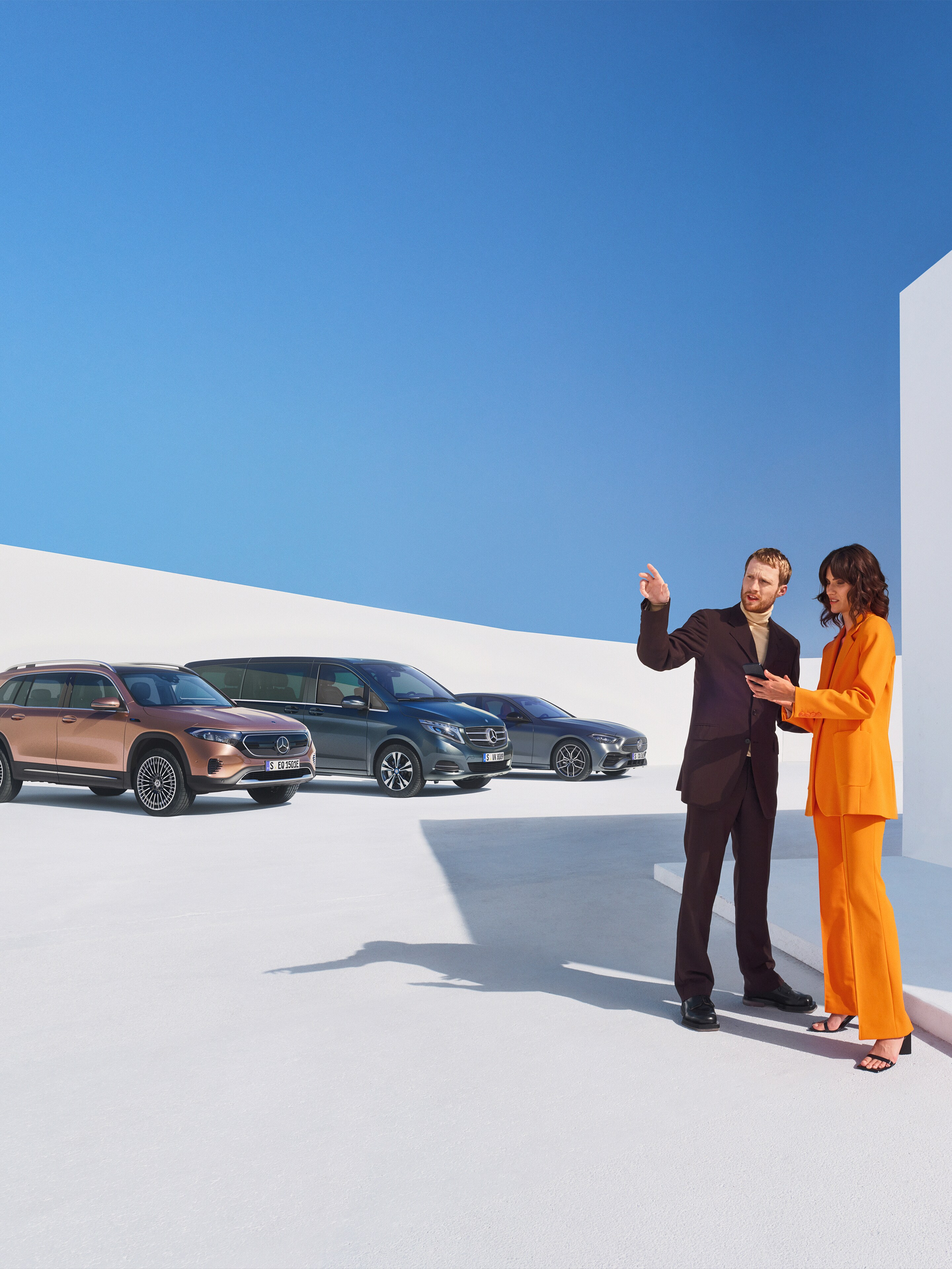 Två personer pratar bredvid en rad av olika Mercedes-Benz modeller