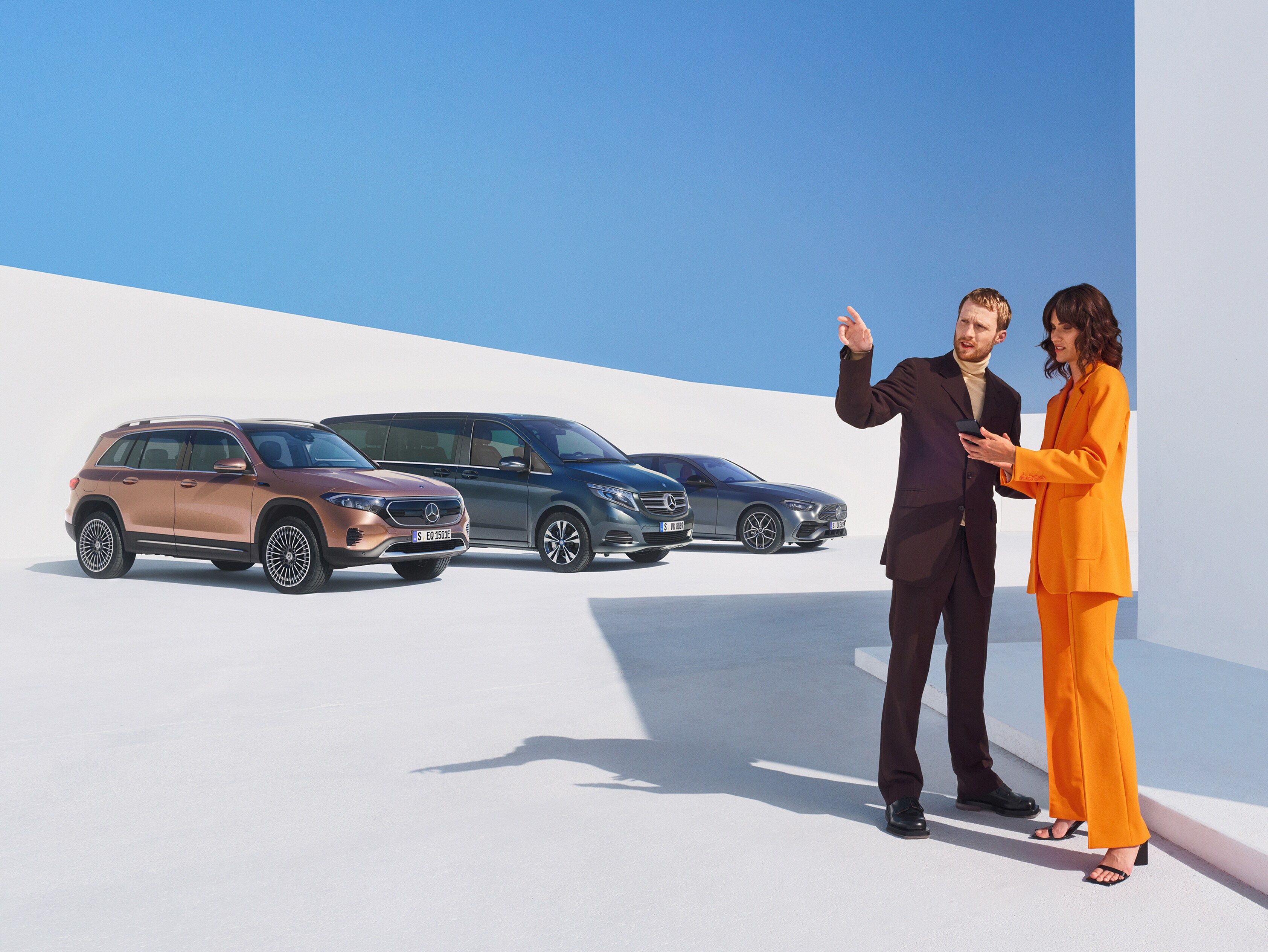 Två personer pratar bredvid en rad av olika Mercedes-Benz modeller
