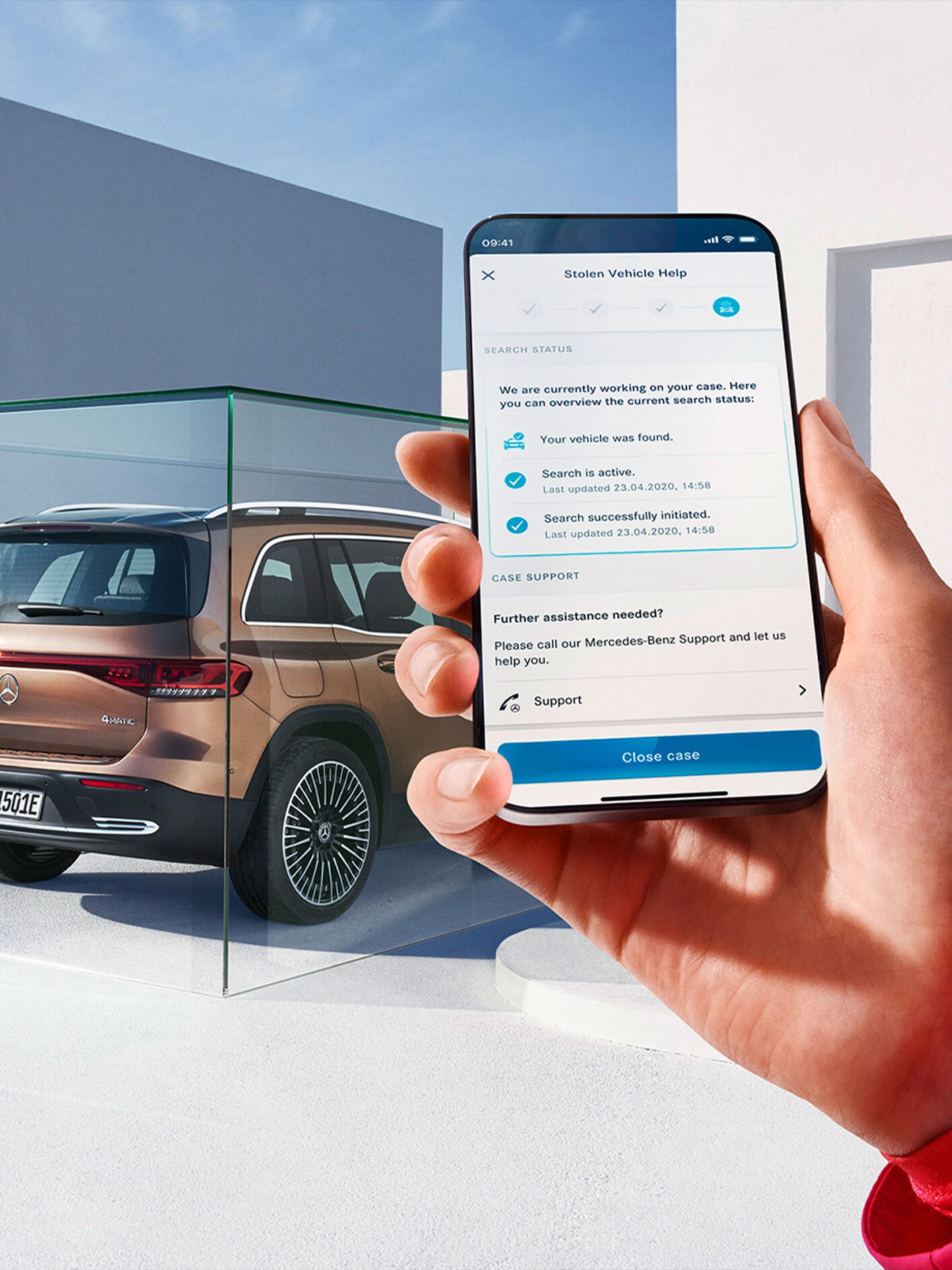 Person använder GUARD 360 på sin smartphone bredvid en Mercedes-Benz EQB.